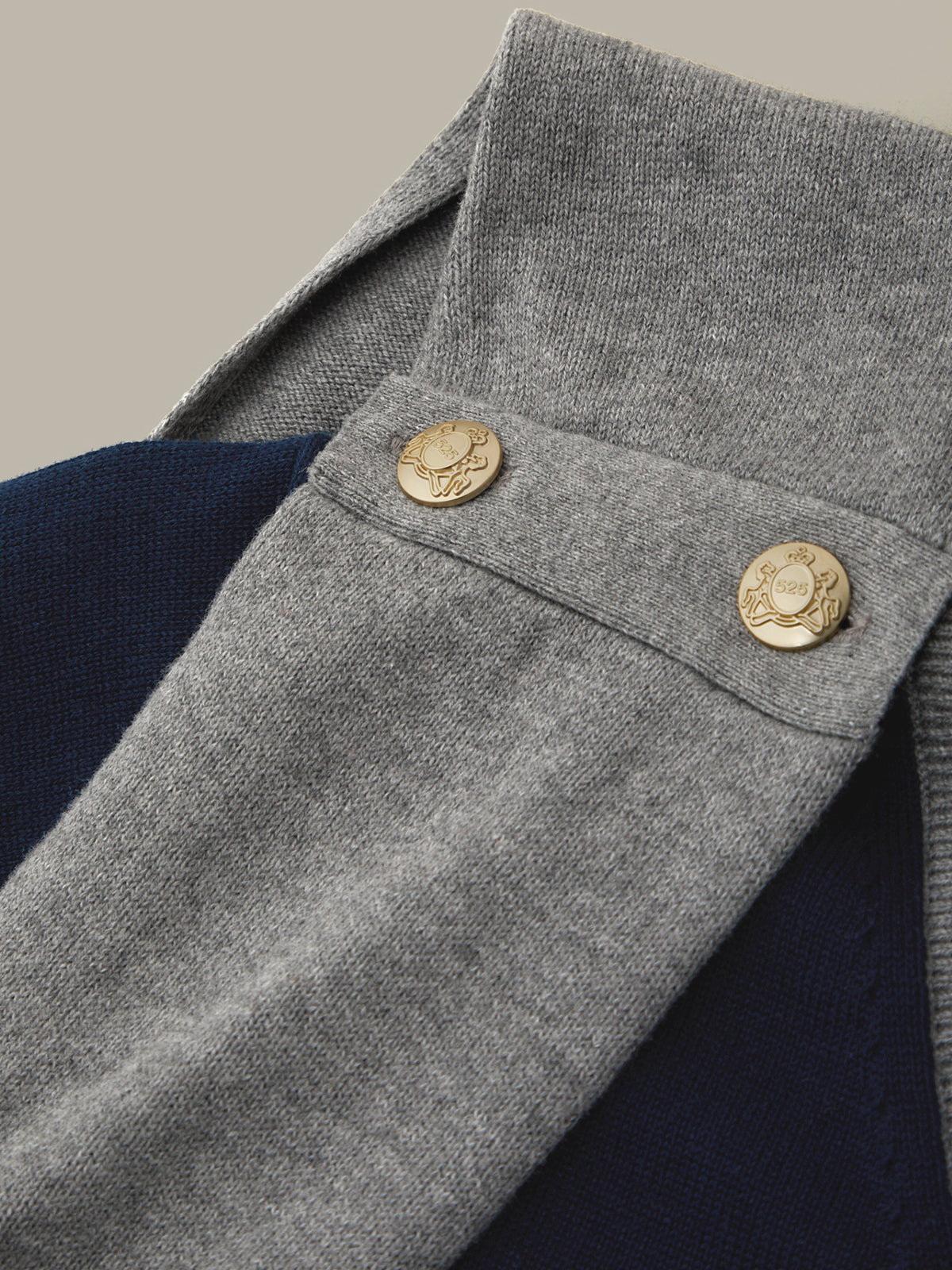Close-up of a gray coat with gold buttons on a neutral background