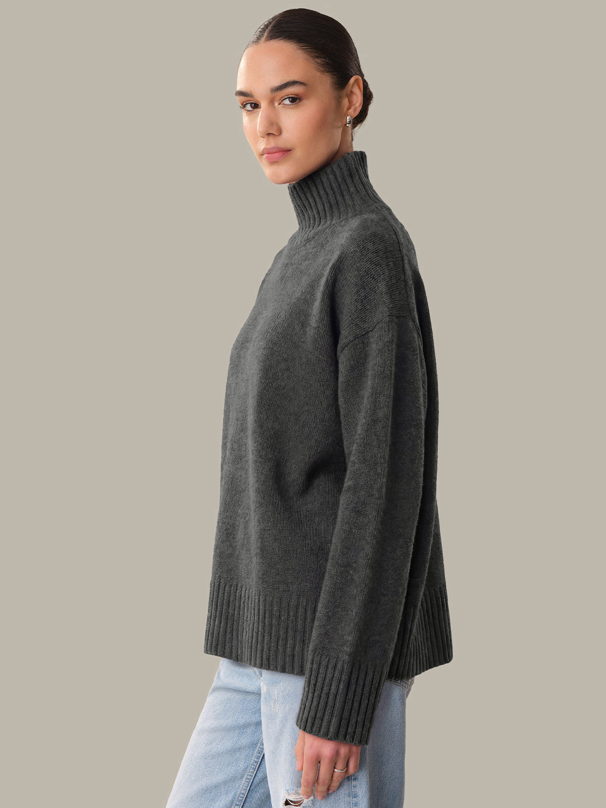 Woman wearing a dark gray turtleneck sweater against a plain background