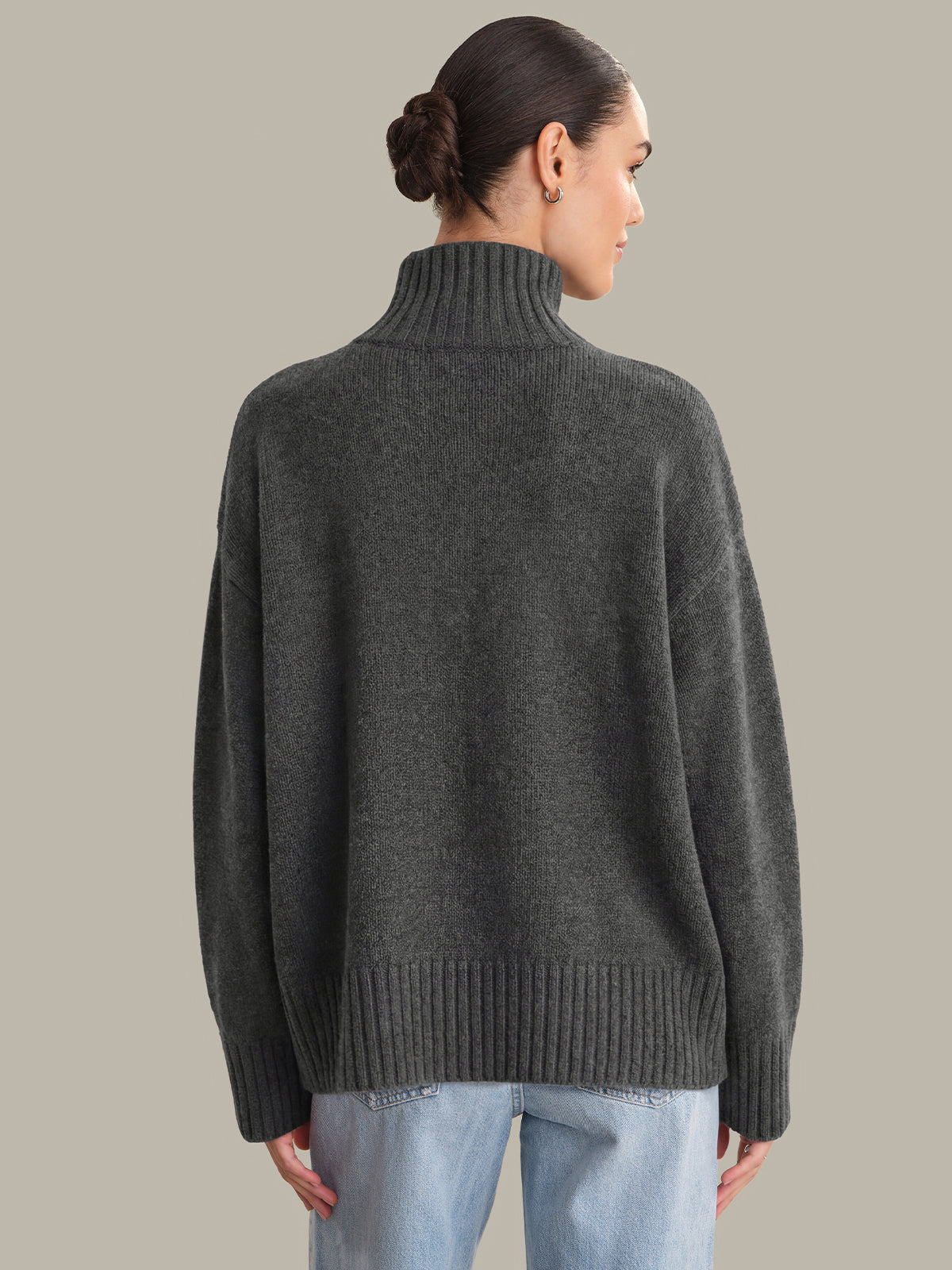 Person wearing a dark gray sweater on a beige background