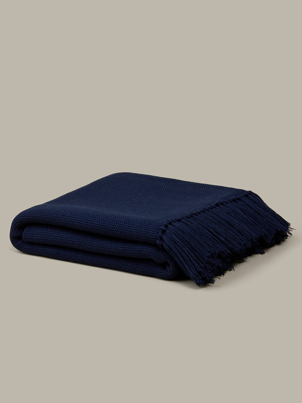 Folded navy blue blanket on a beige background