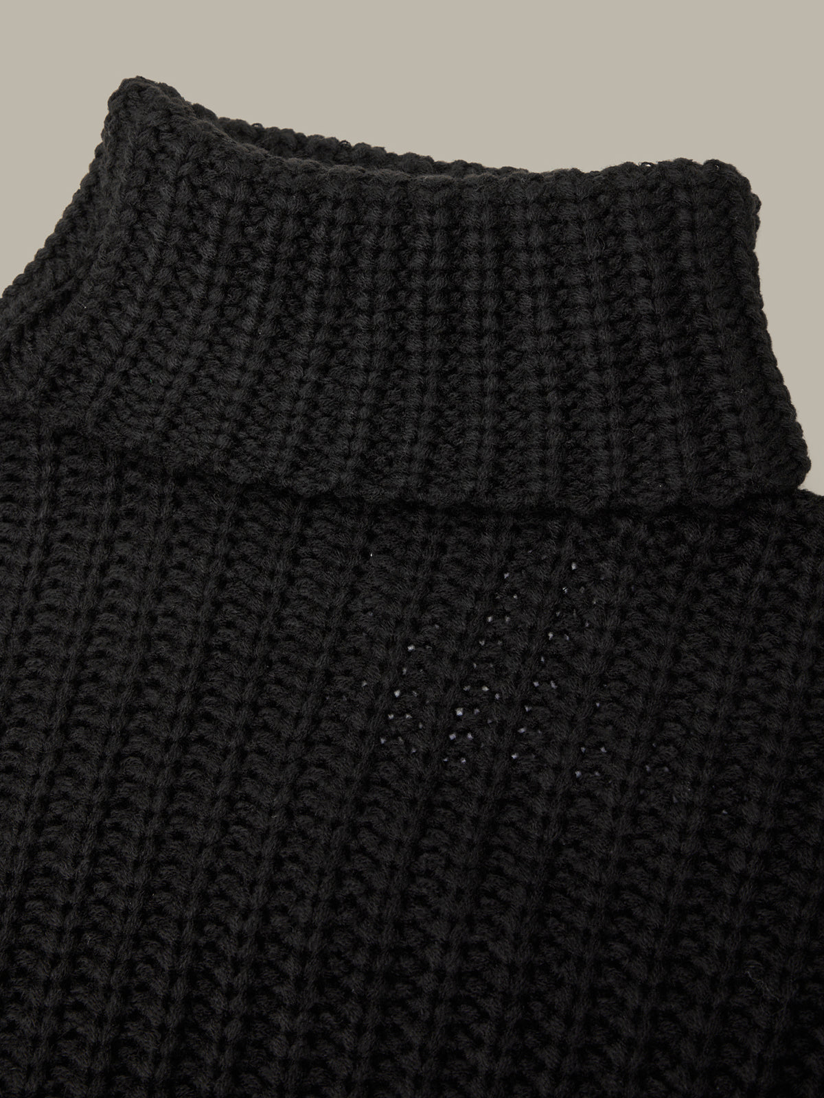 Close-up of a black knitted garment with a textured pattern.