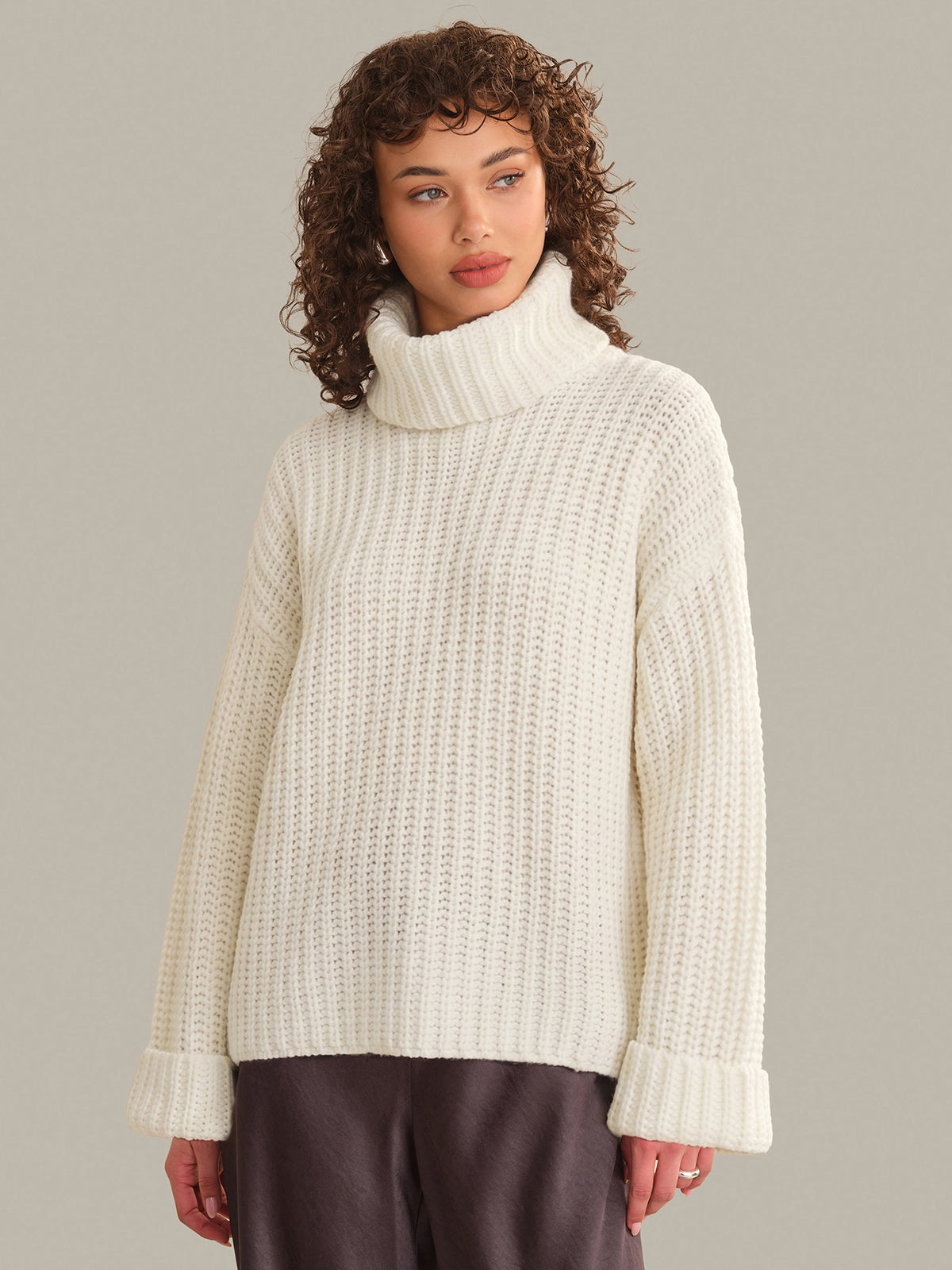 Woman wearing a cream turtleneck sweater against a plain background