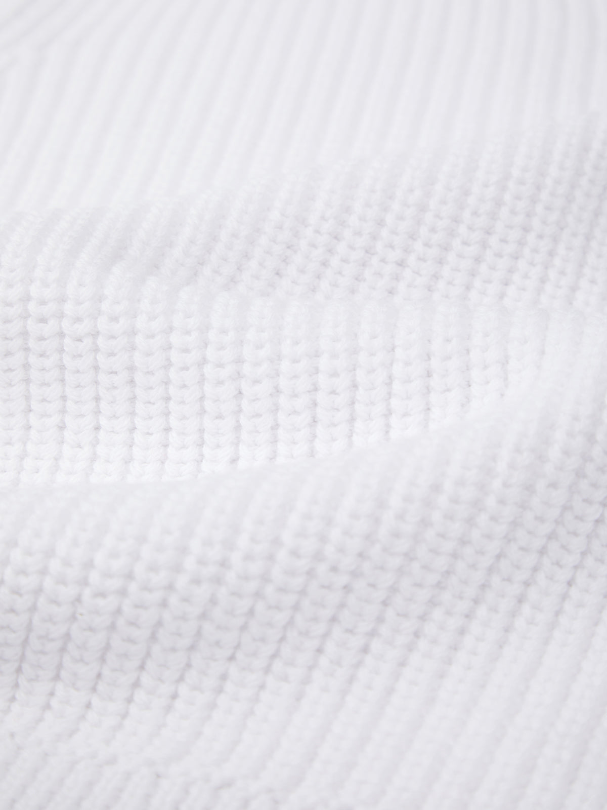 Close-up of 525 America’s white, ribbed knit fabric made from 100% cotton, highlighting its textured parallel lines and soft folds.