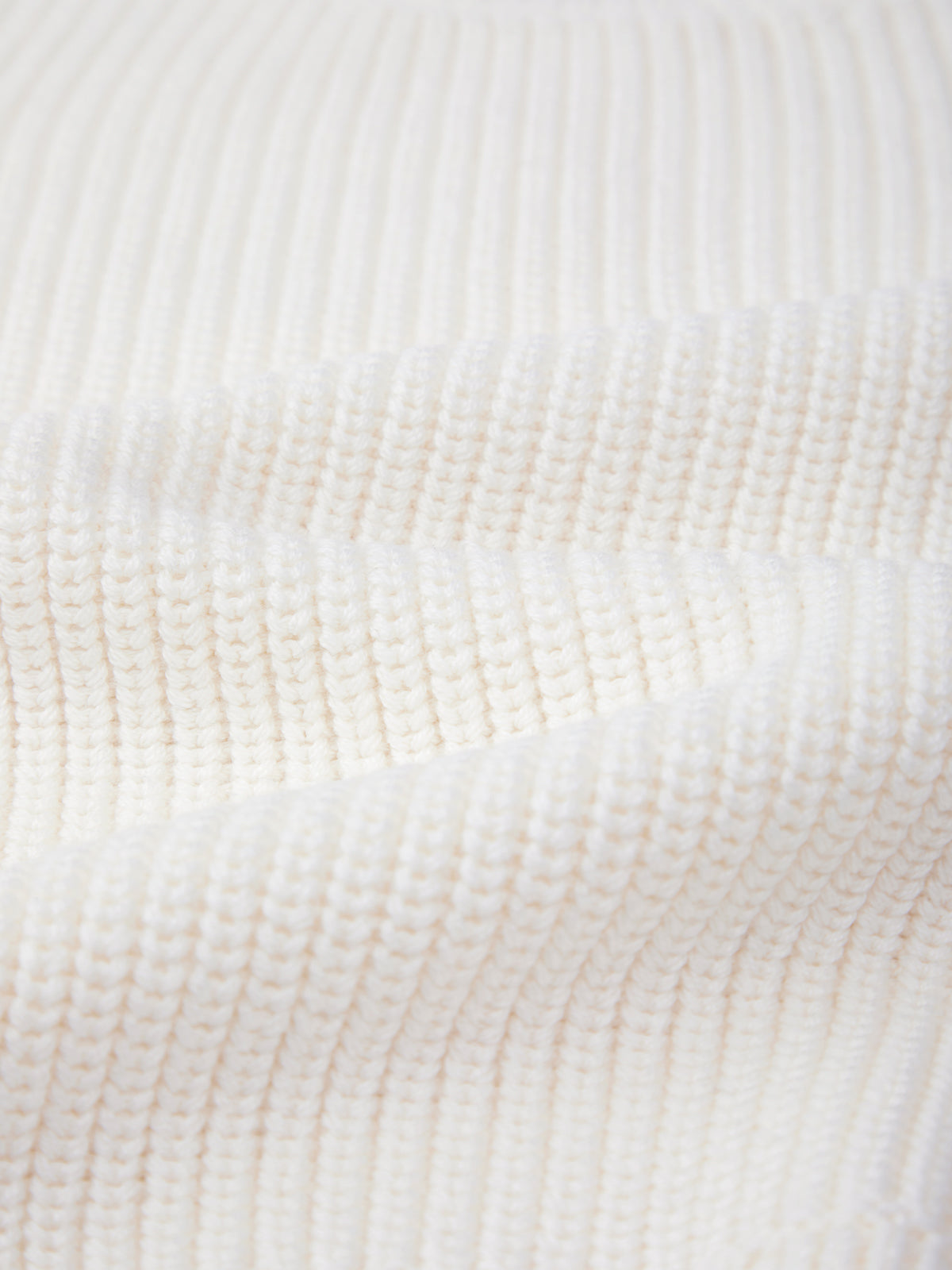 Close-up of a ribbed, white knitted fabric from 525 America, featuring a wavy texture and detailed stitch pattern—crafted from 100% cotton for casual comfort.