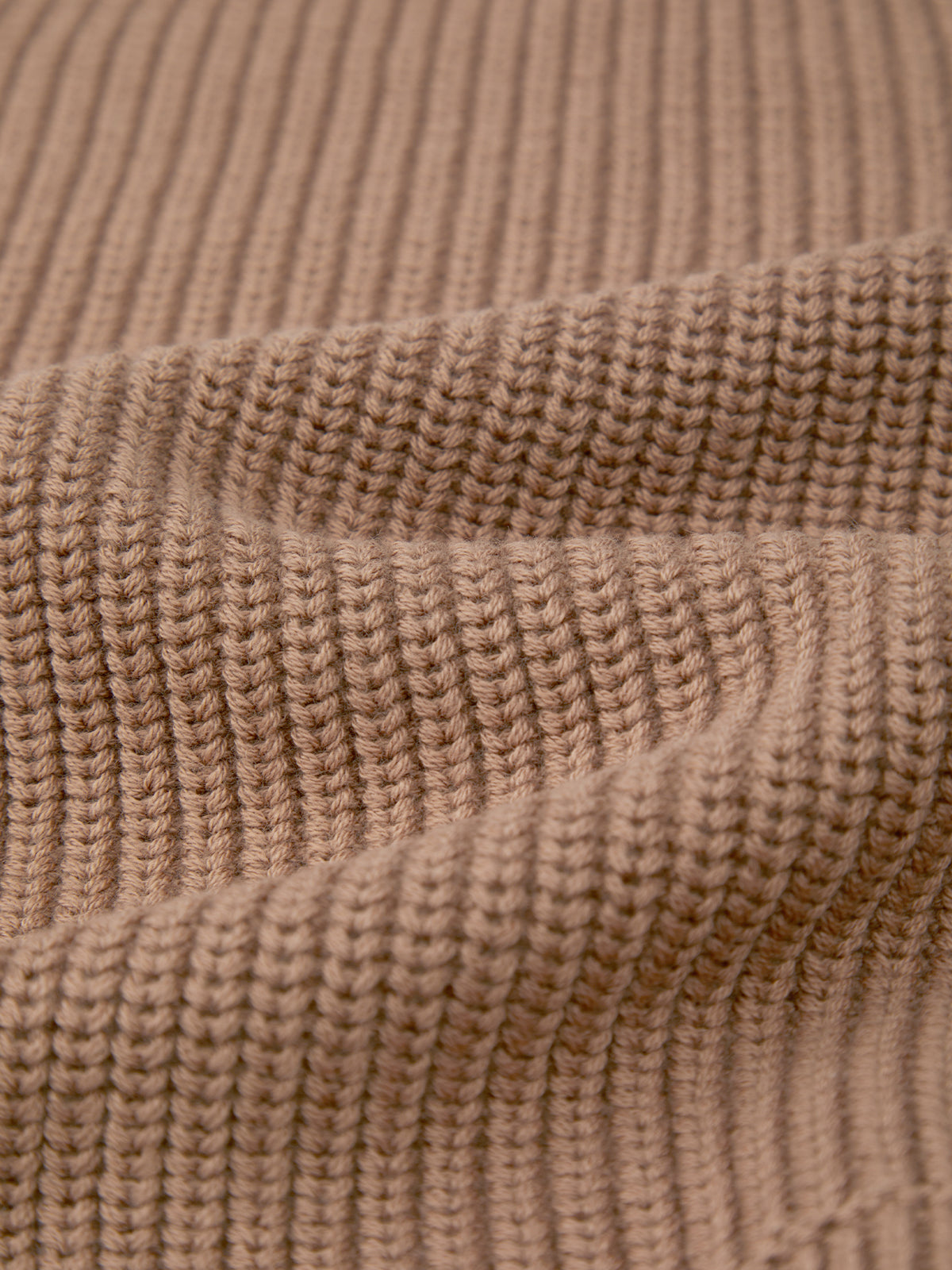 Close-up of 525 America’s ribbed knitted fabric in light brown/beige, crafted from 100% cotton with visible texture and folds creating shadows and depth.