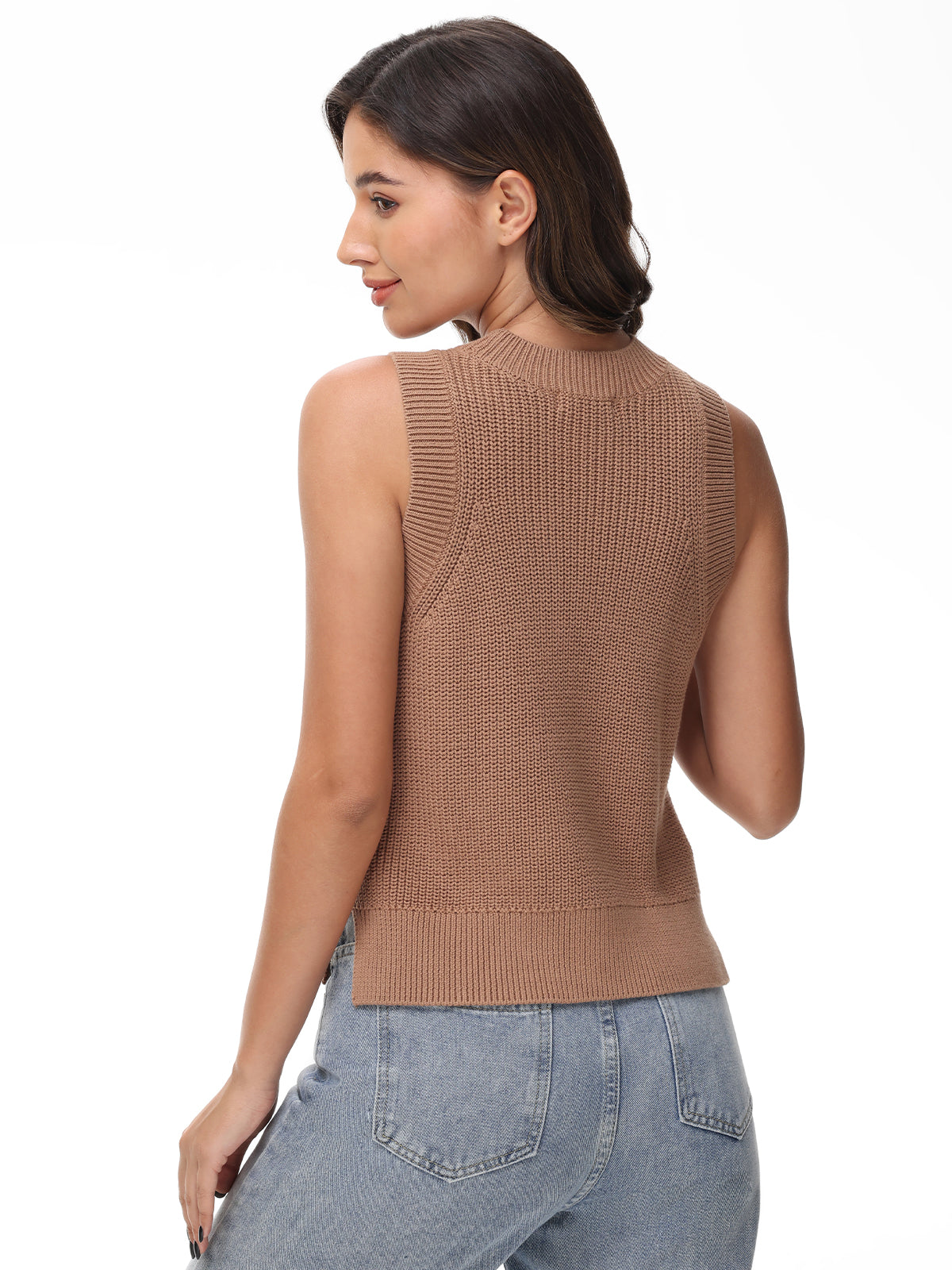 A woman with brown hair exudes chic simplicity on a plain white background, wearing a sleeveless, 100% cotton knit top in light brown by 525 America, paired with light blue jeans.