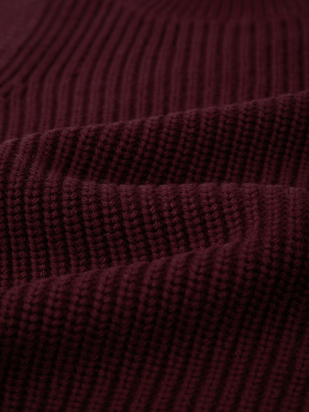 Close-up of a ribbed, dark burgundy knit by 525 America, highlighting the detailed horizontal ridges and weave of this 100% cotton fabric, commonly used in comfortable casual crew neck styles.