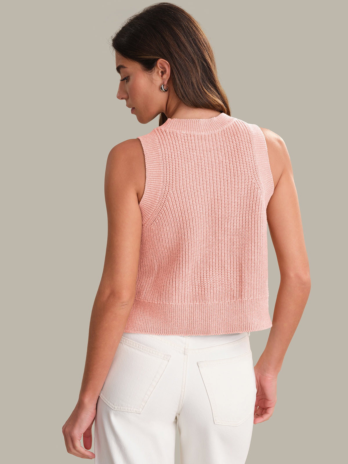 Woman wearing a pink knitted sleeveless top against a neutral background