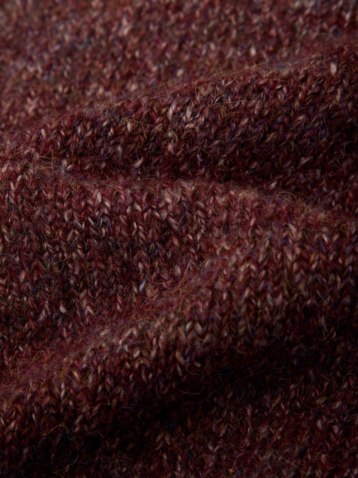 Close-up of a dark brown and burgundy heathered knit fabric texture with soft folds.