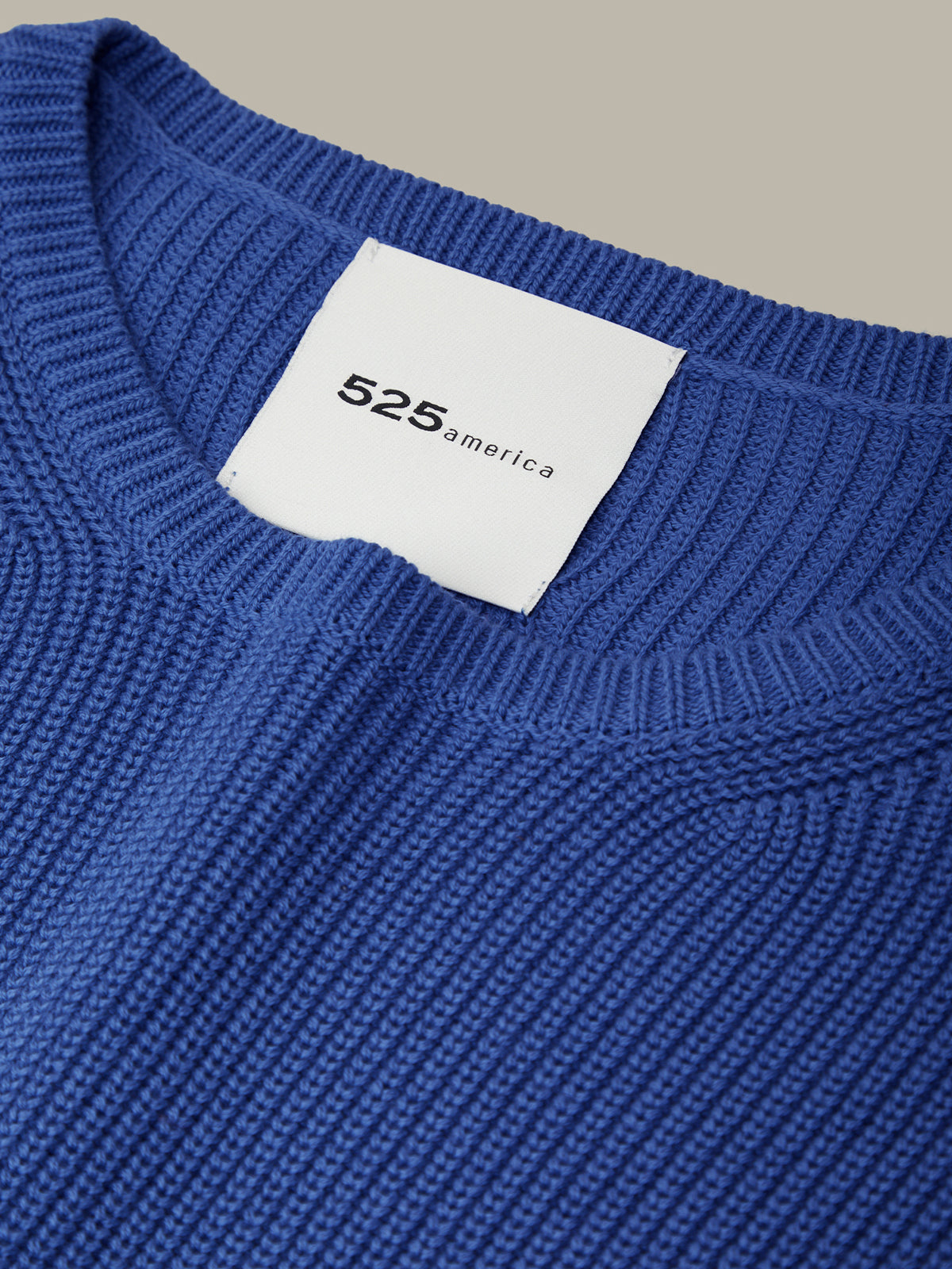 Close-up of a blue sweater with a white label displaying '525 america'.