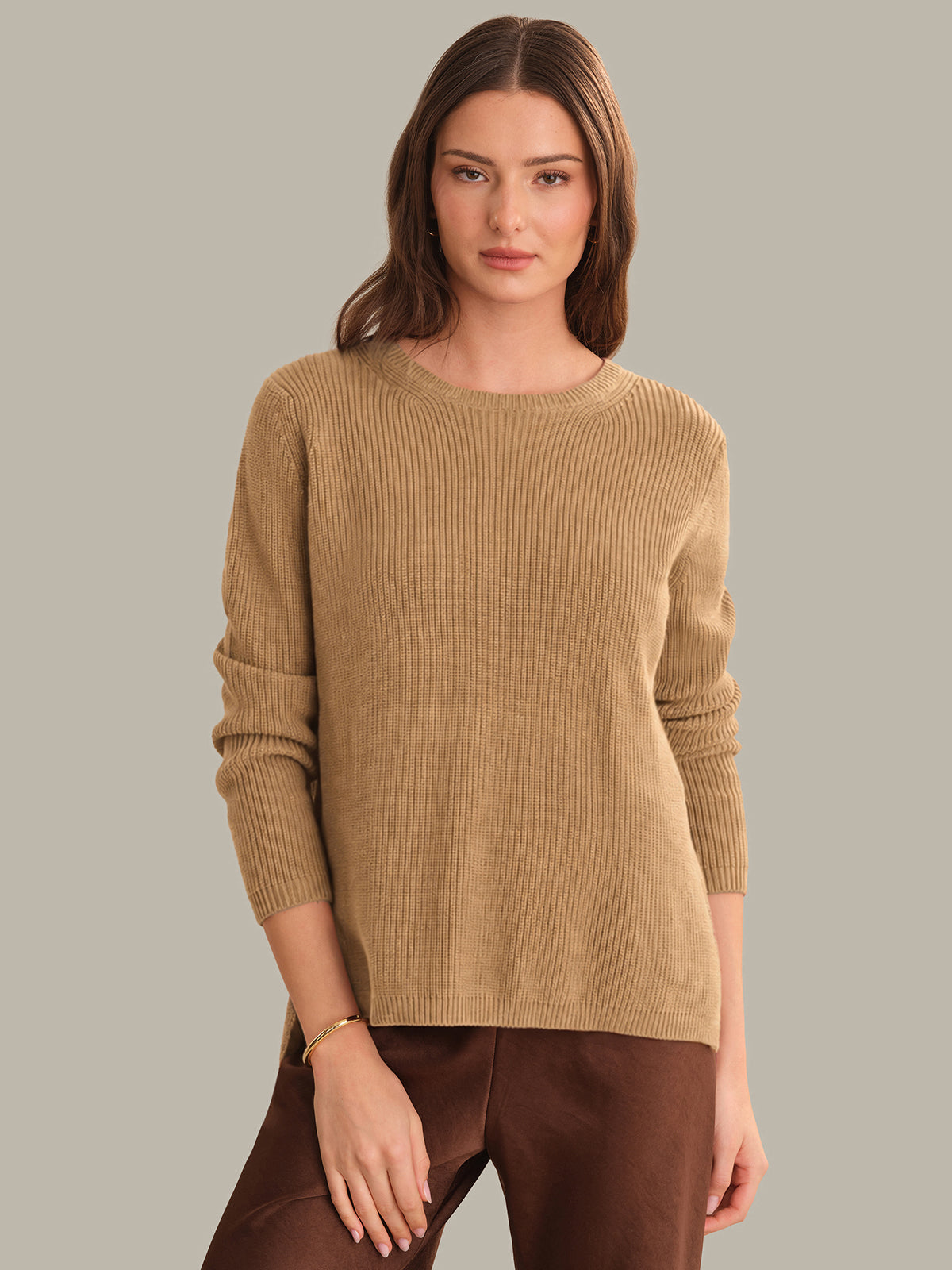 Woman wearing a beige sweater against a neutral background
