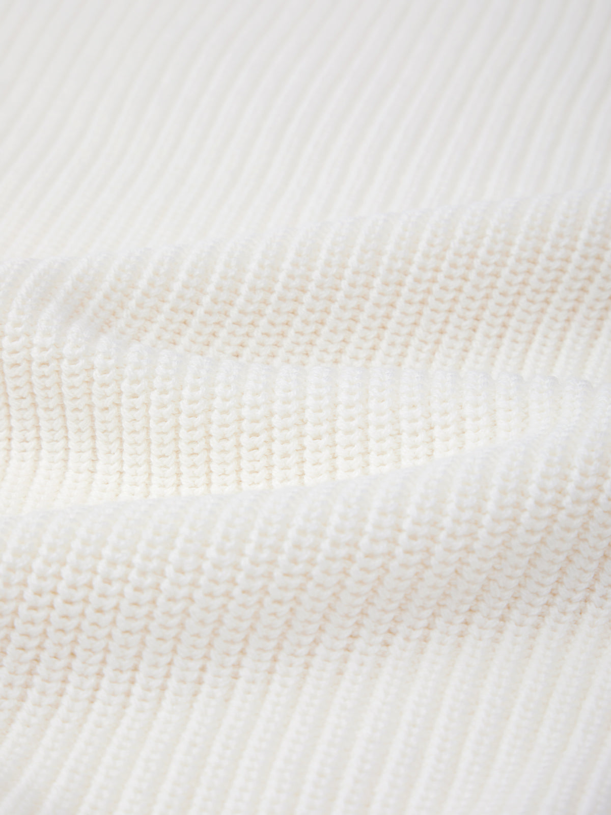 Close-up of 525 Americas white ribbed knit fabric, crafted from 100% cotton and featuring a textured shaker stitch pattern with gentle waves.