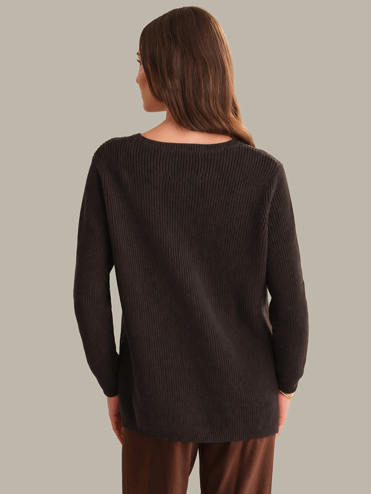 Woman wearing a dark brown sweater against a plain background