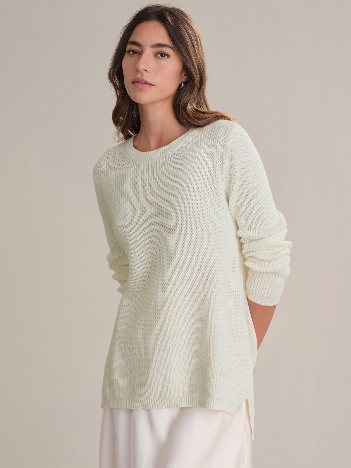 Woman wearing a white sweater against a plain background