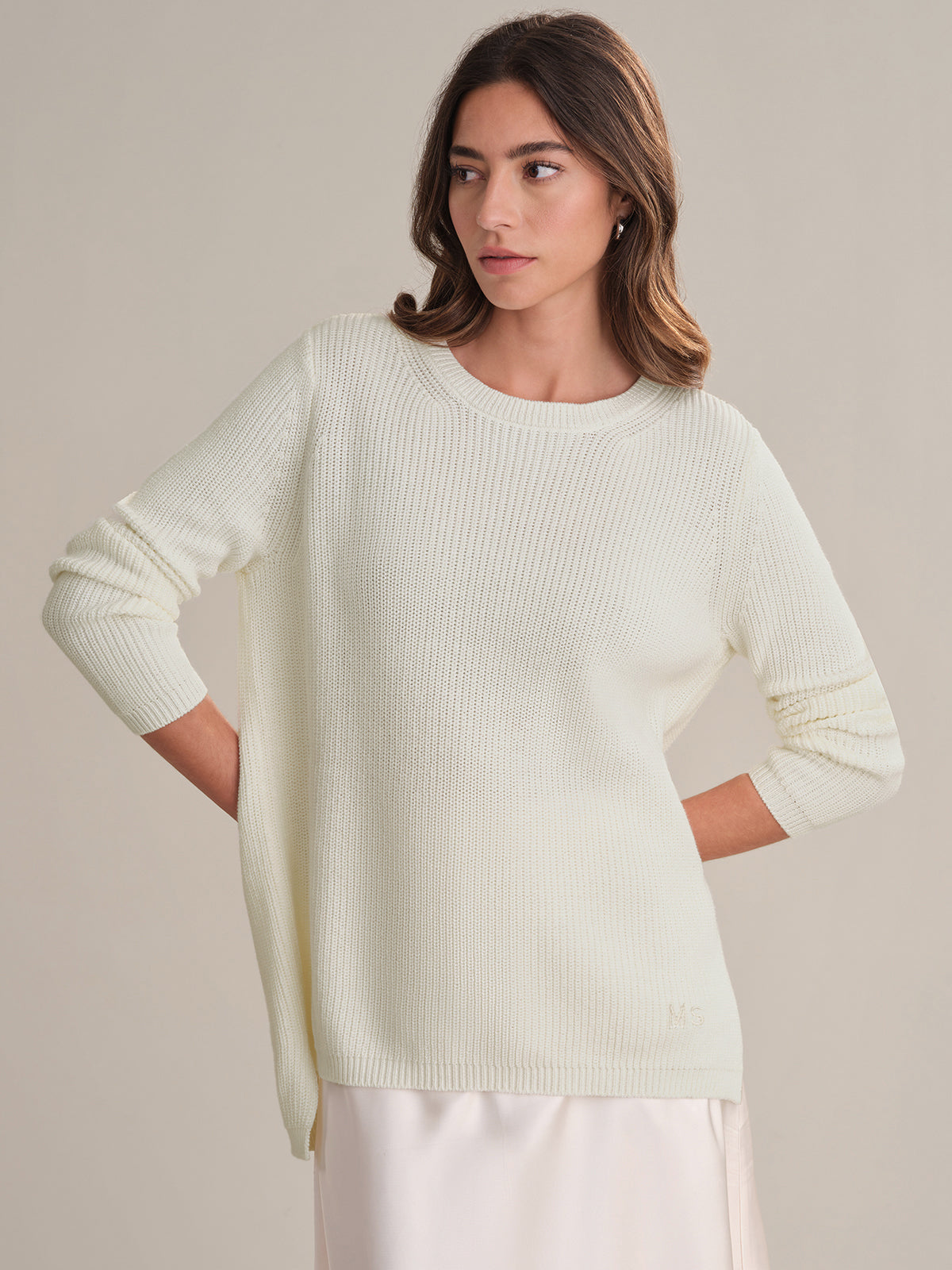 Woman wearing a white sweater against a neutral background