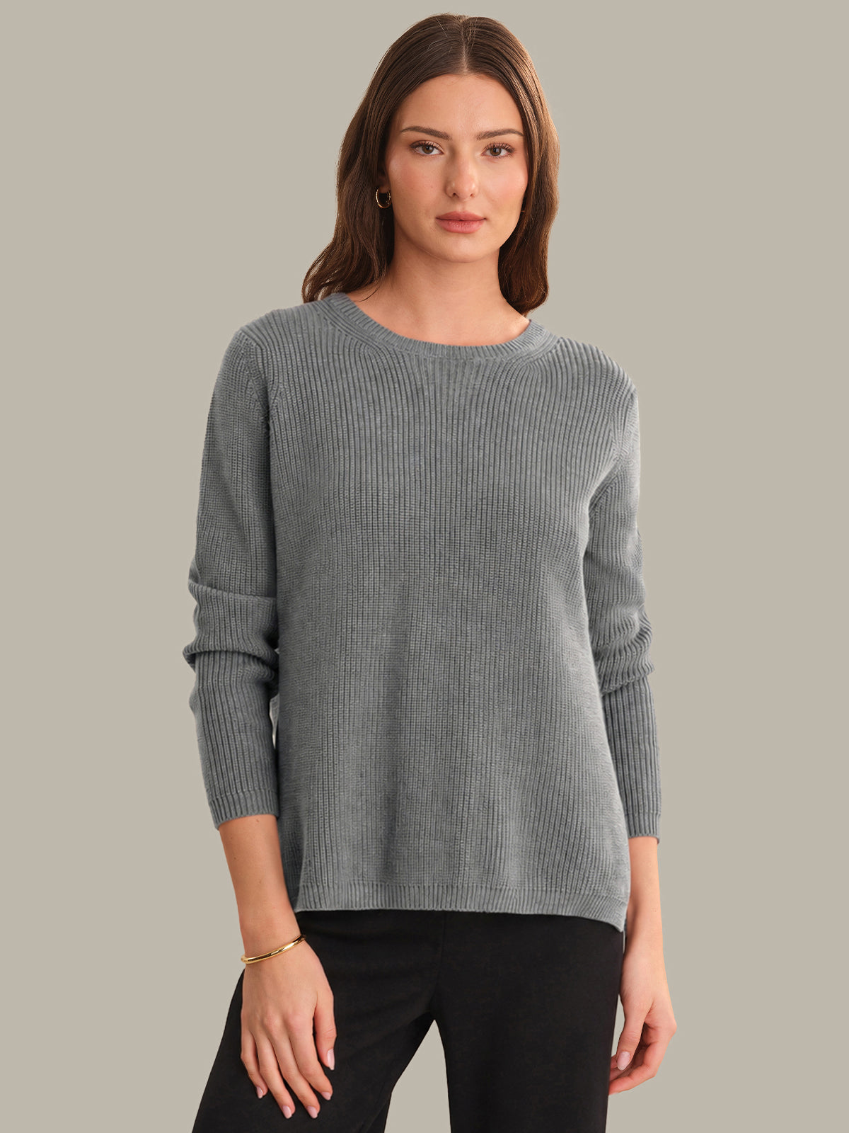 Woman wearing a gray sweater against a plain background