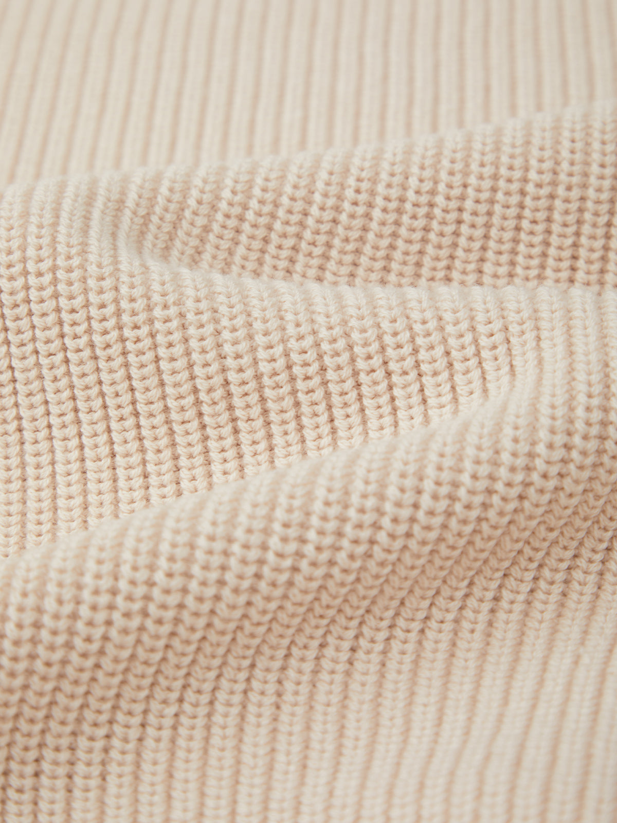 Close-up of a beige ribbed knit fabric by 525 America, crafted from 100% cotton with wavy texture and visible horizontal shaker stitch rows.