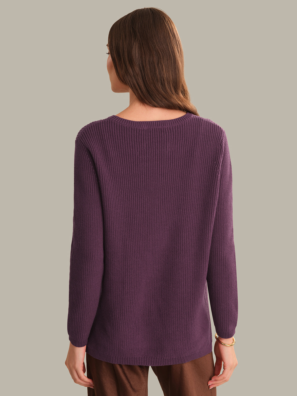 Person wearing a purple sweater on a plain background