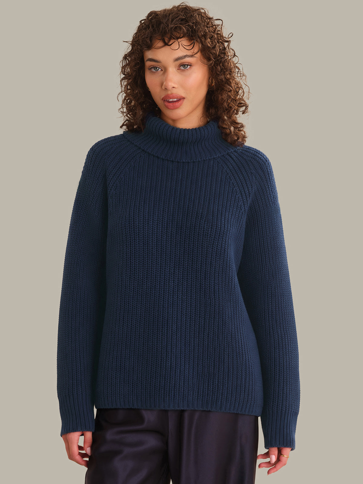 Woman wearing a blue ribbed sweater against a neutral background