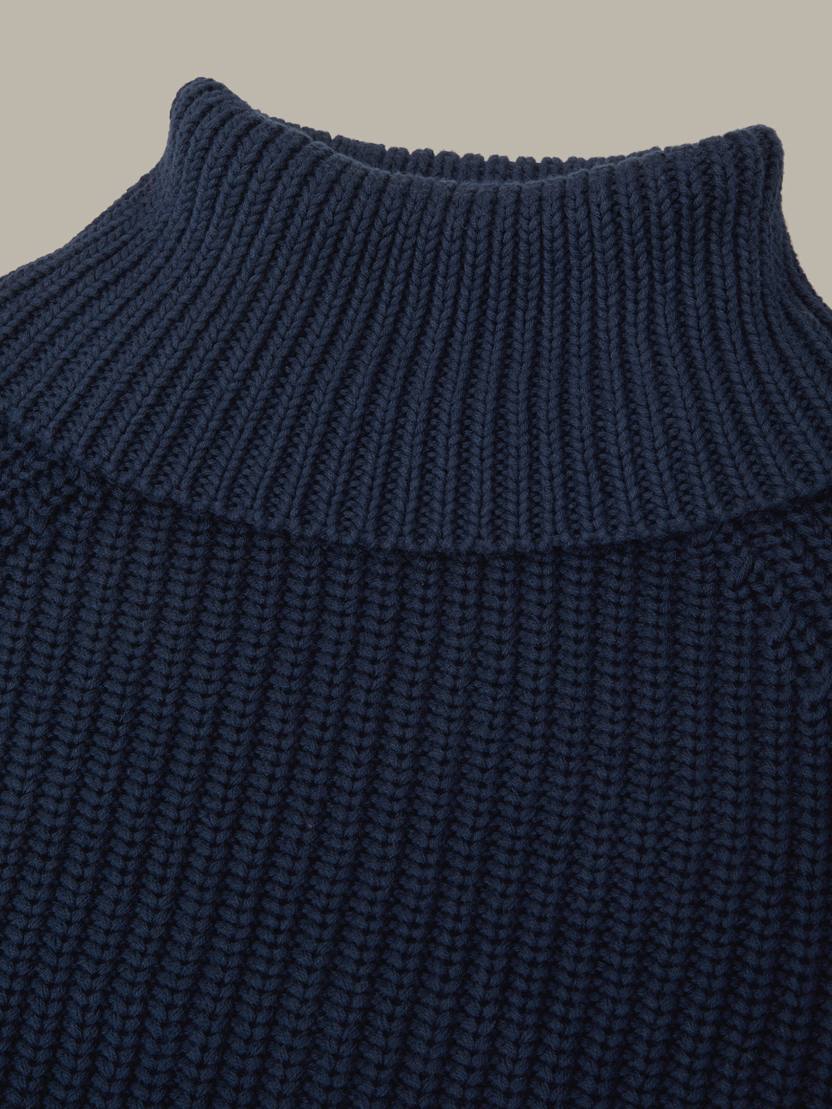 Close-up of a navy blue ribbed knit sweater collar on a beige background