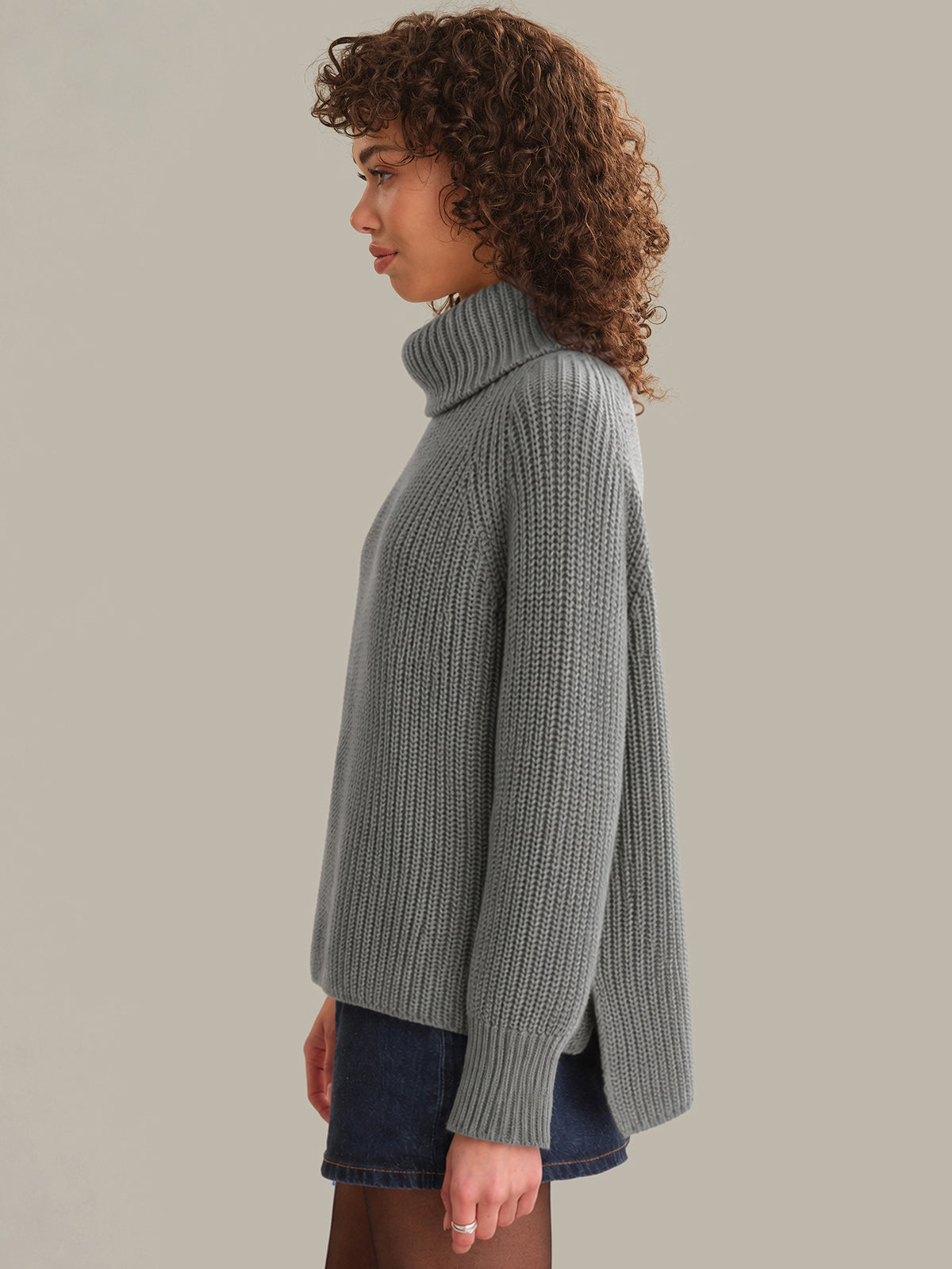 Woman wearing a gray knitted sweater against a plain background