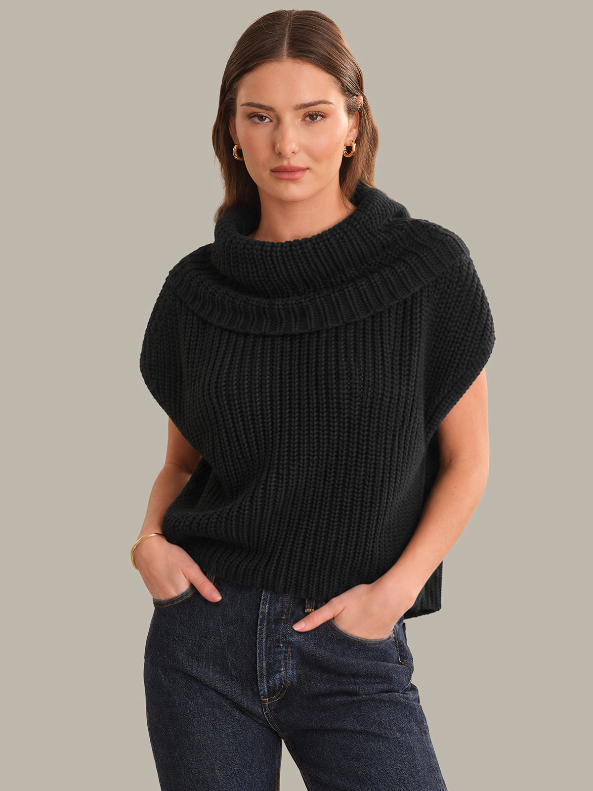 Woman wearing a black ribbed sweater against a gray background