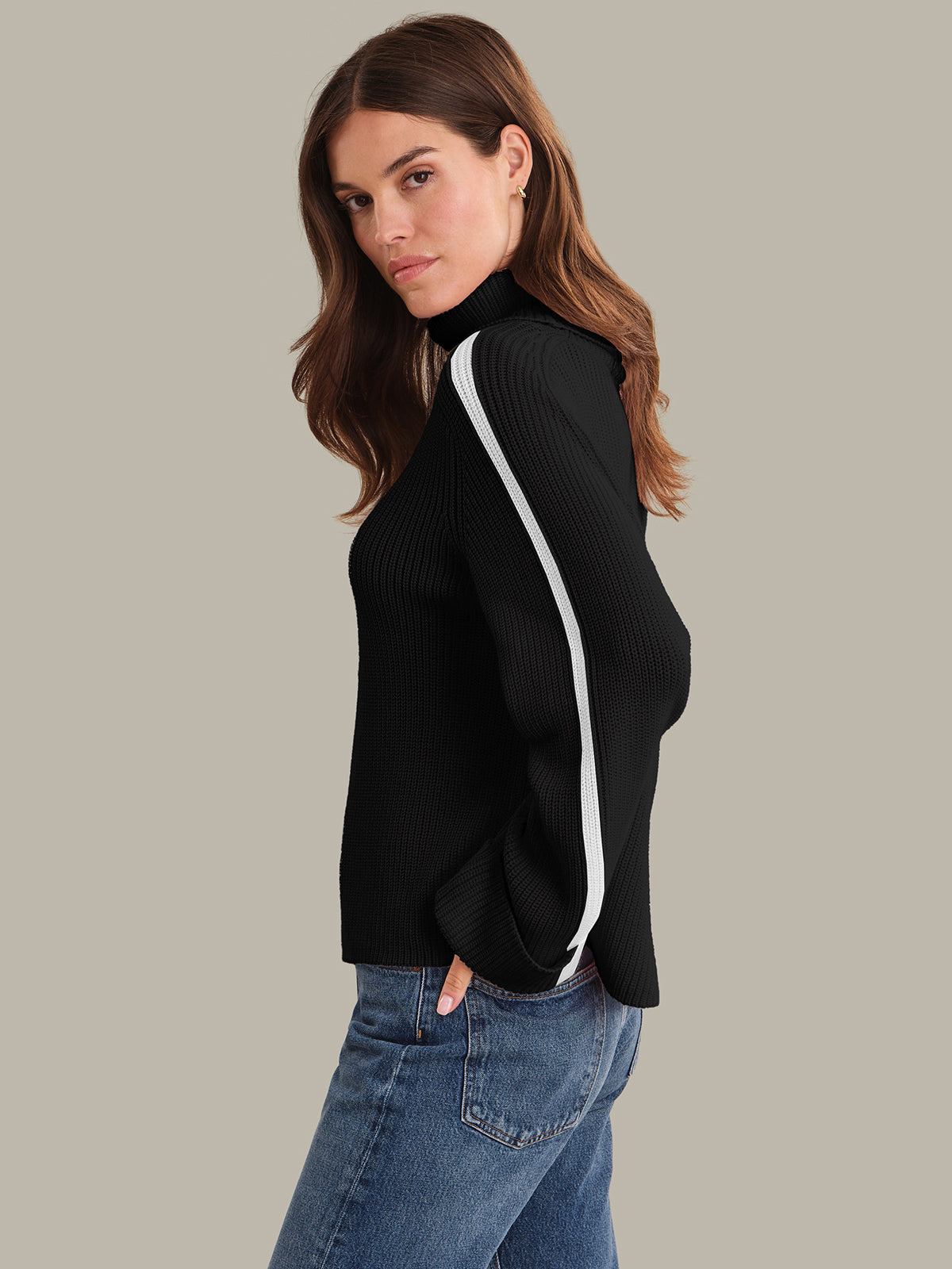 Woman wearing a black turtleneck sweater with white stripes on a gray background