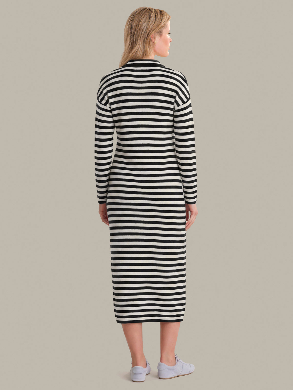 Woman wearing a black and white striped dress against a plain background