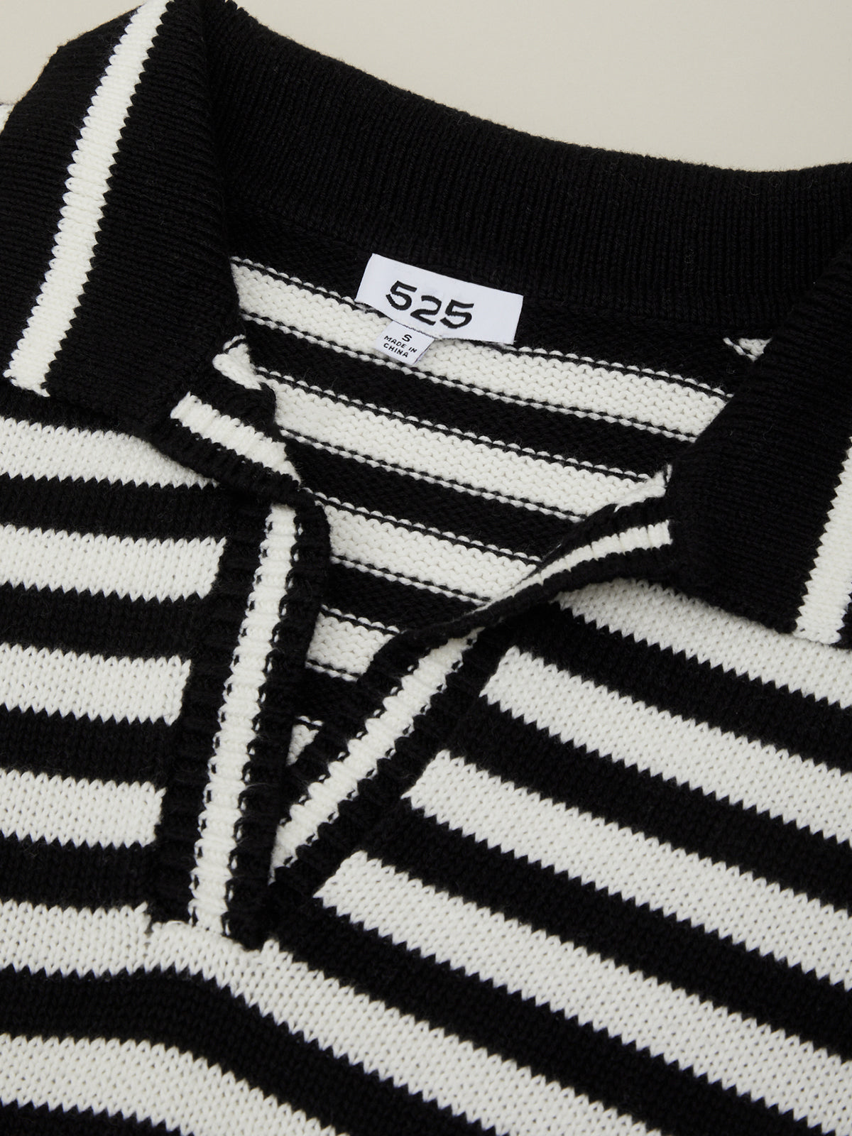Black and white striped sweater with a brand label on a neutral background
