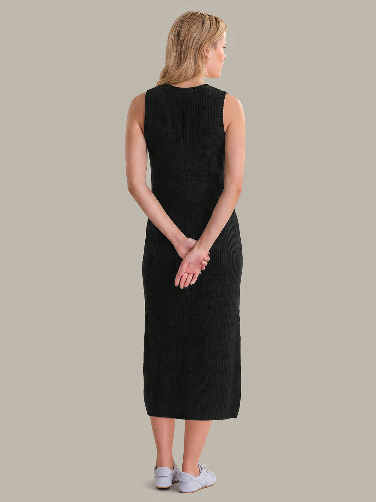 Woman wearing a black sleeveless dress against a plain background