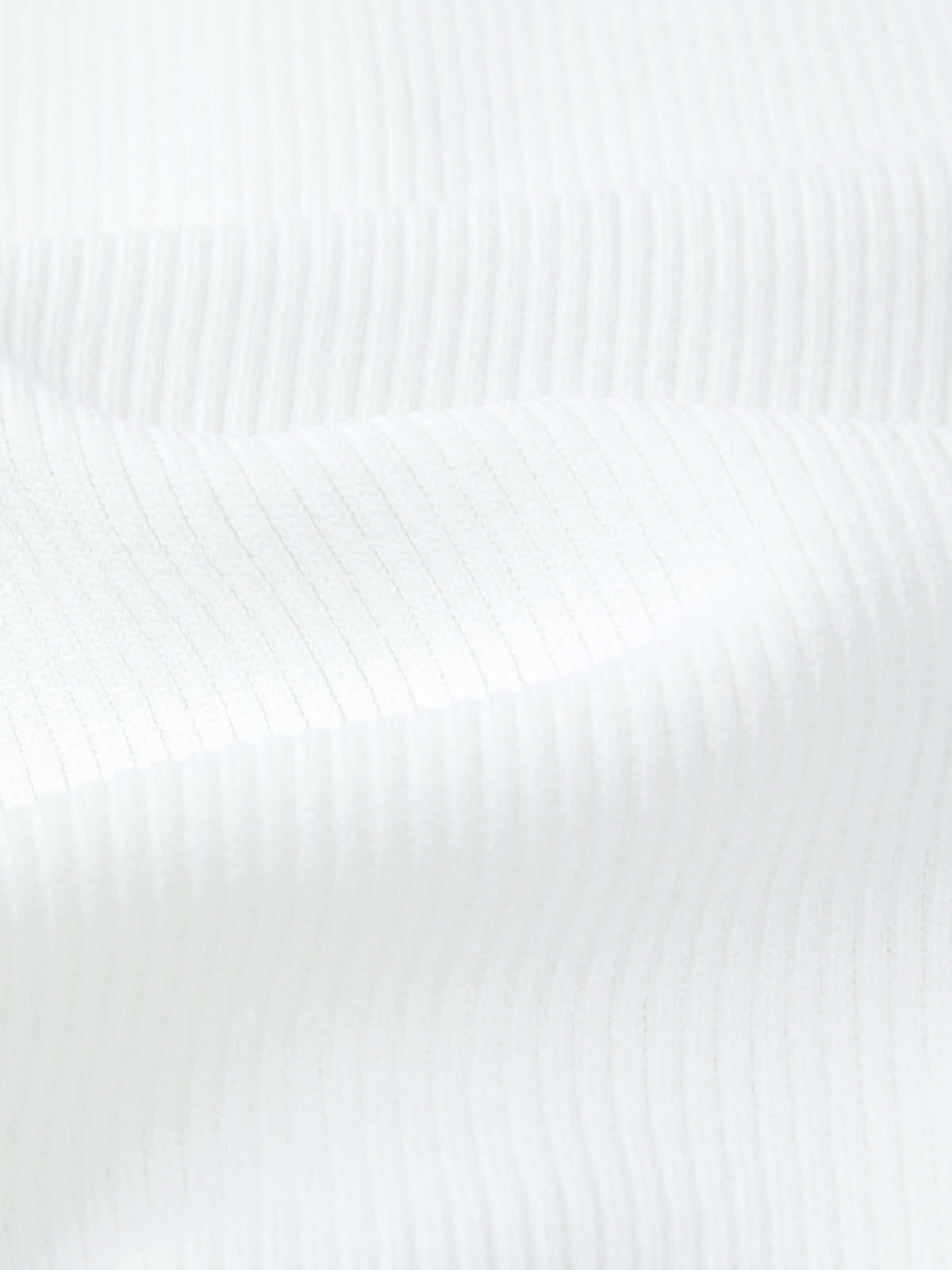 Close-up of white ribbed fabric with vertical lines and gentle folds, creating subtle shadows and texture—ideal for a sporty look or as a stylish 525 America polo sweater.