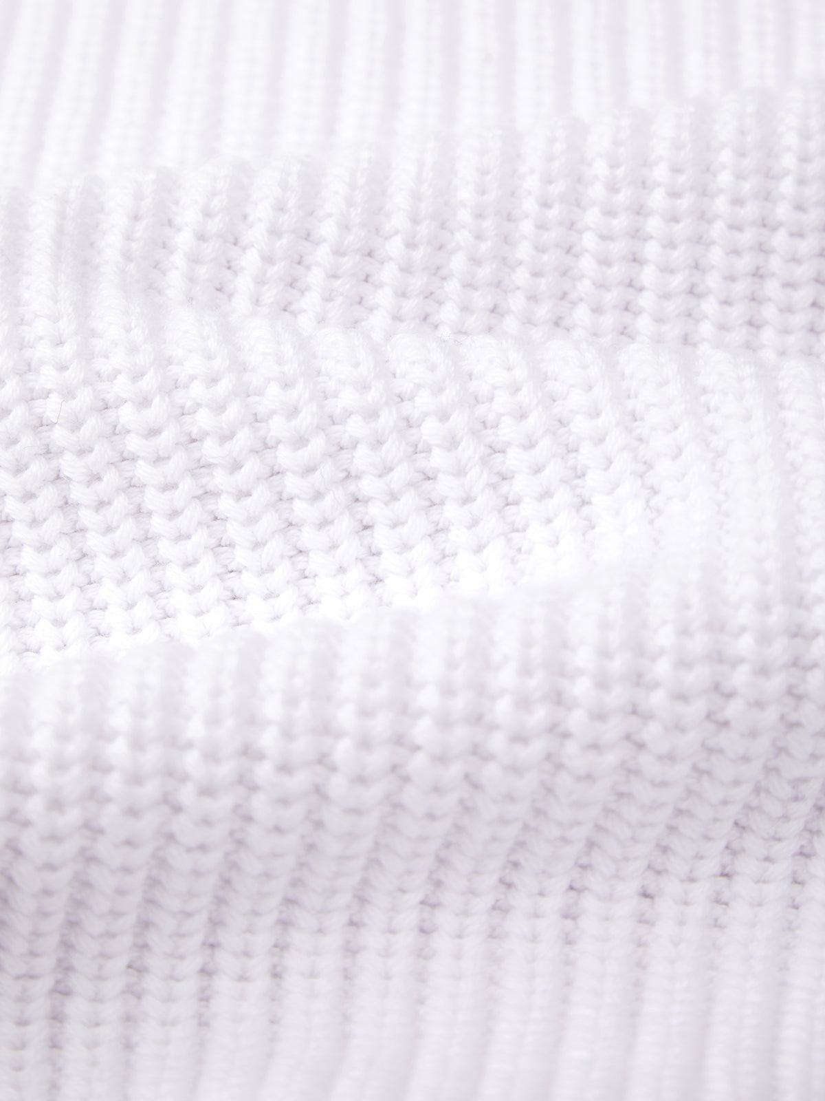 Close-up of a textured white knitted fabric by 525 America, crafted from breathable cotton with evenly spaced horizontal rows and a soft, wavy surface.