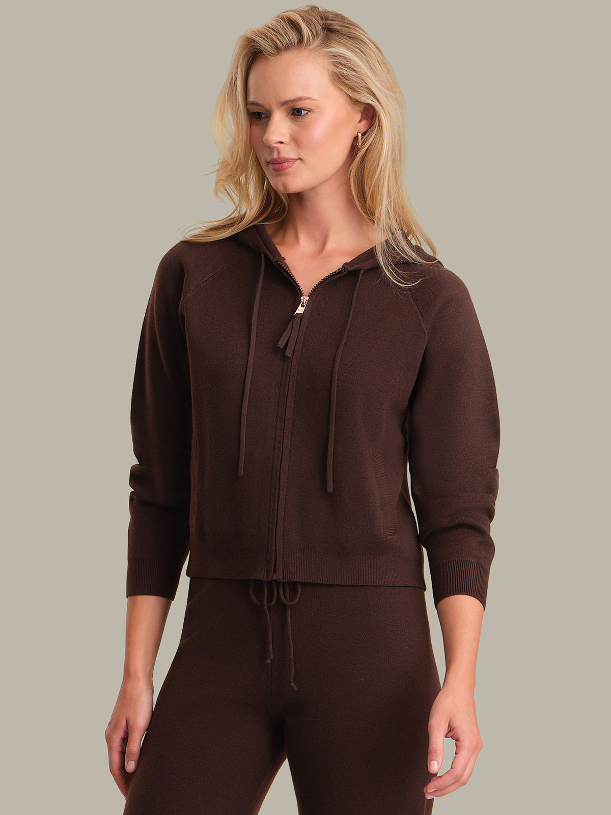 Woman wearing a brown tracksuit against a plain background