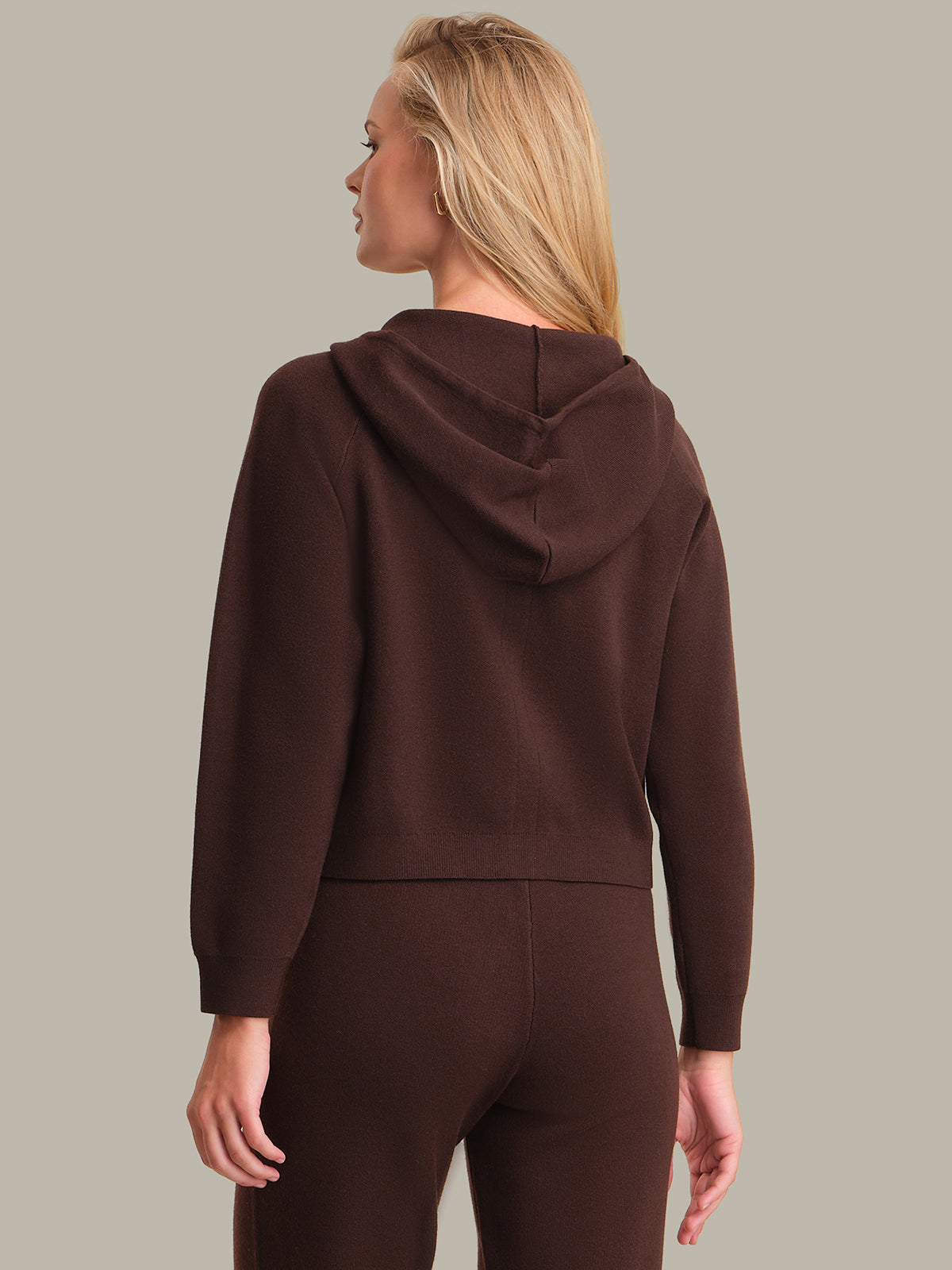 Person wearing a brown hoodie and pants on a plain background