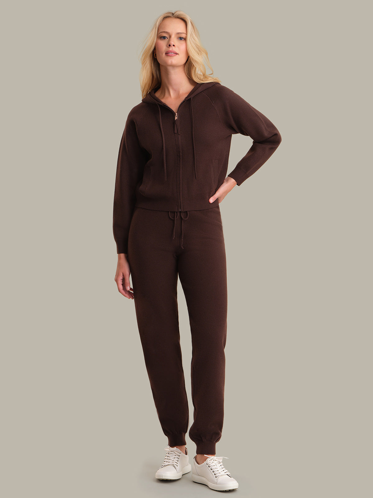 Woman wearing a brown tracksuit on a gray background