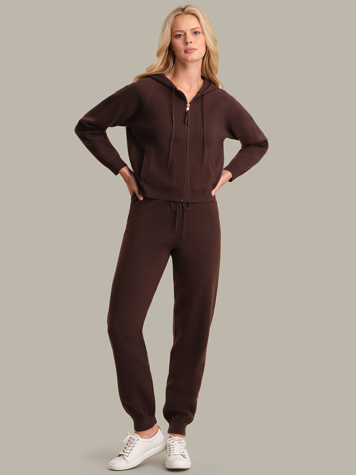 Woman wearing a brown sweatpants against a gray background