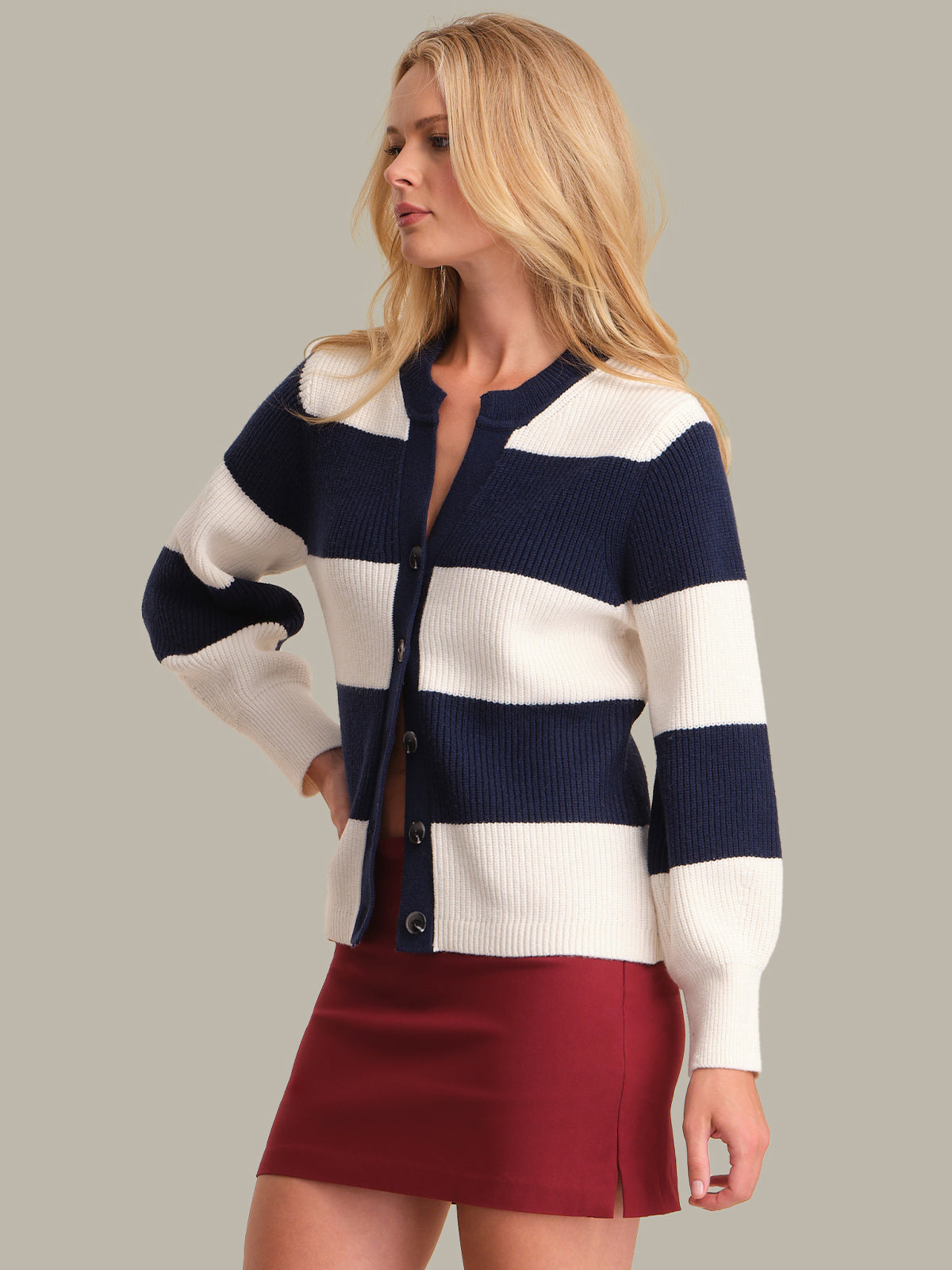 Woman wearing a striped cardigan with navy and white horizontal stripes on a plain background