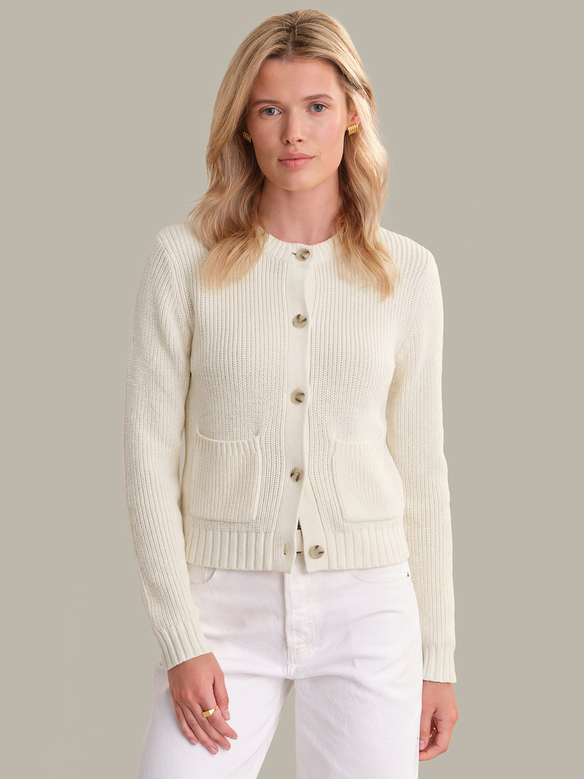Woman wearing a cream cardigan over a white top against a neutral background