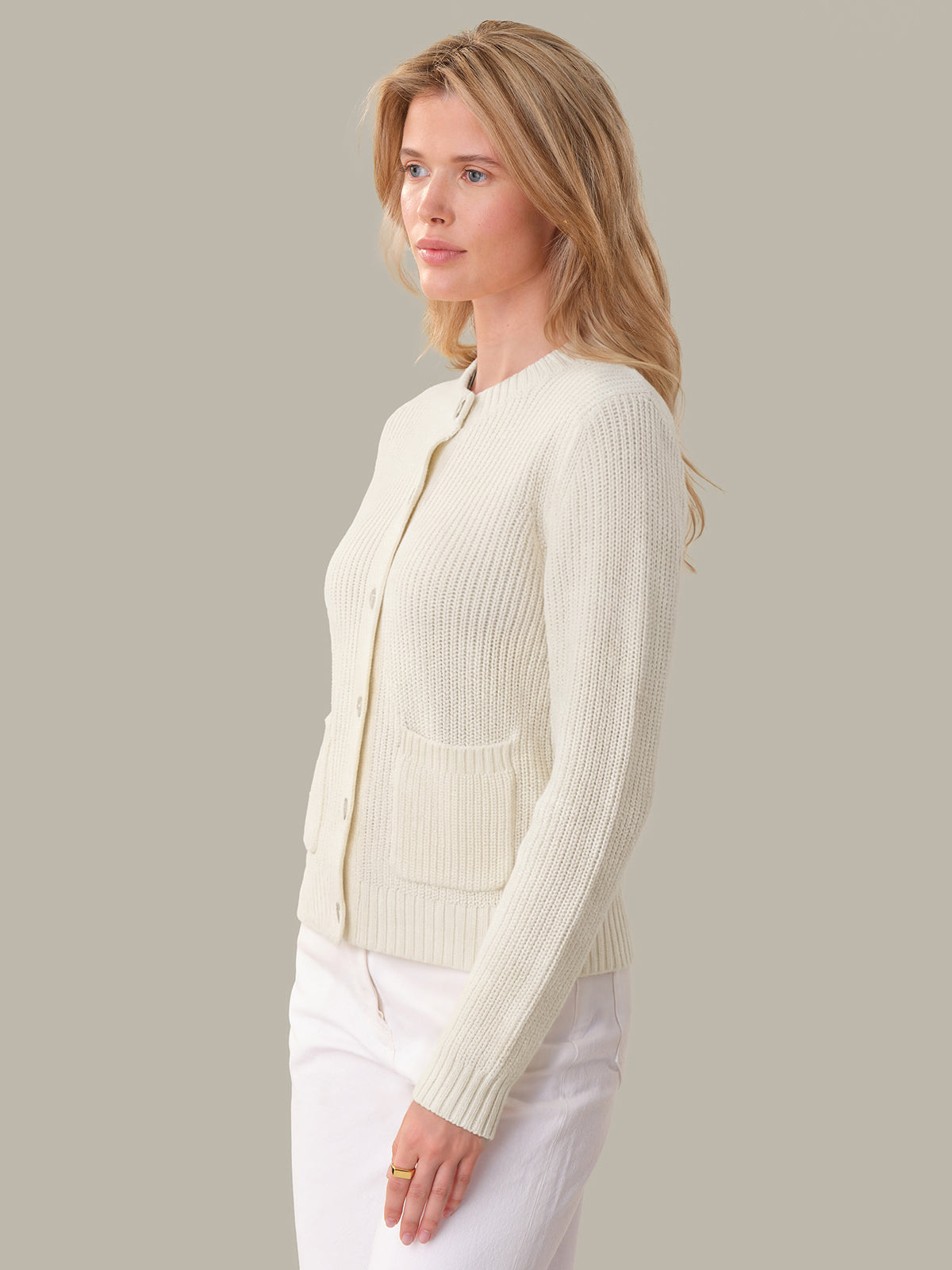 Woman wearing a cream-colored cardigan against a plain background