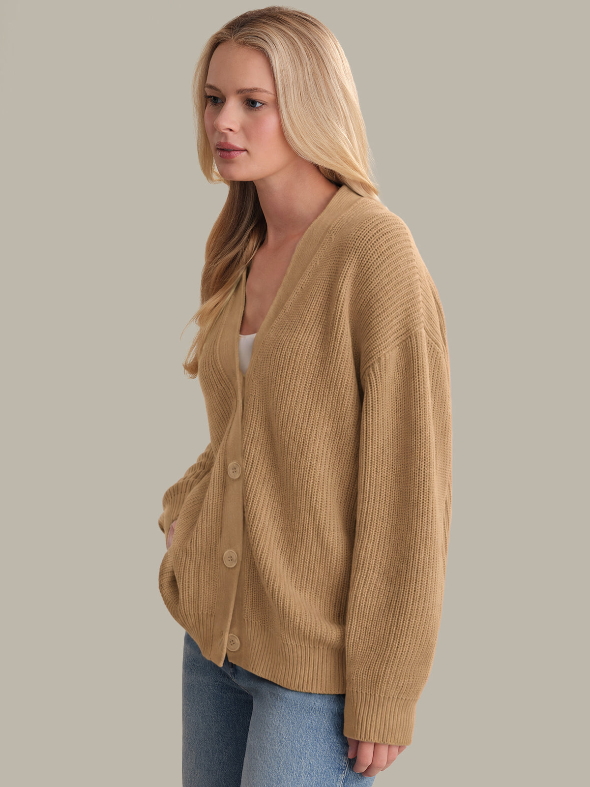 Woman wearing a beige cardigan against a plain background