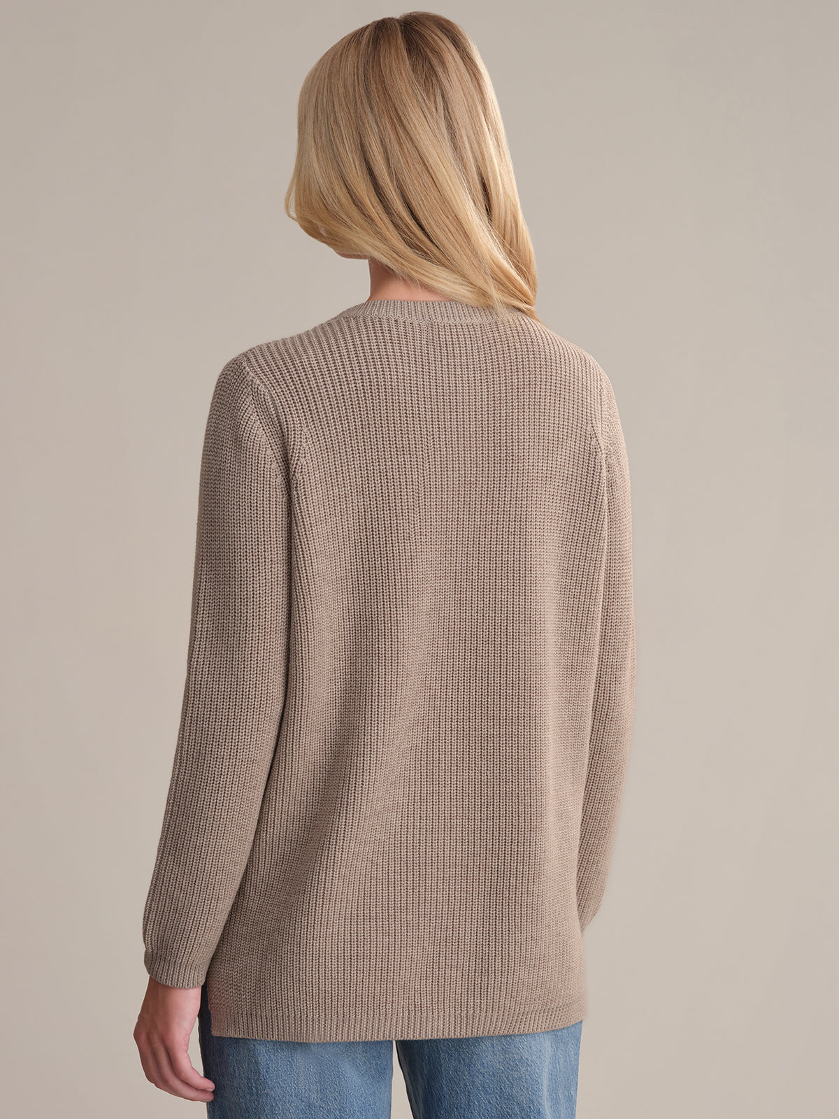 Person wearing a brown ribbed sweater on a beige background