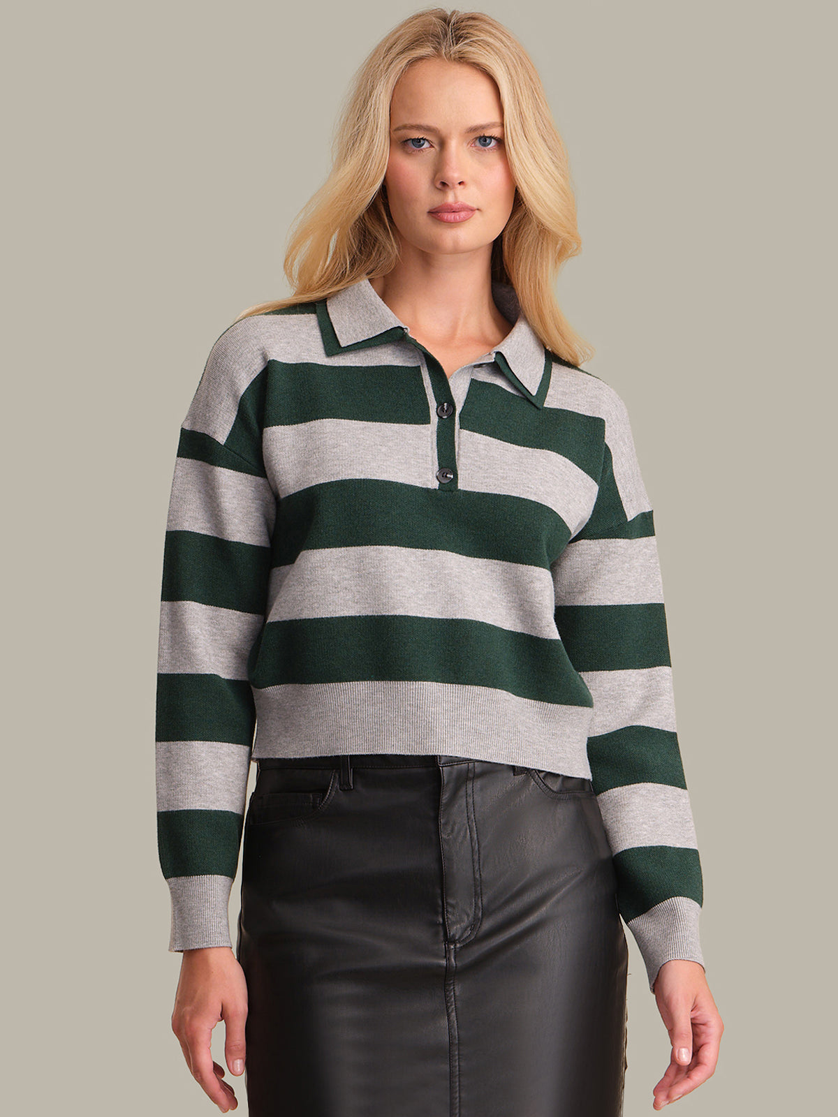 Woman wearing a green and gray striped sweater against a plain background