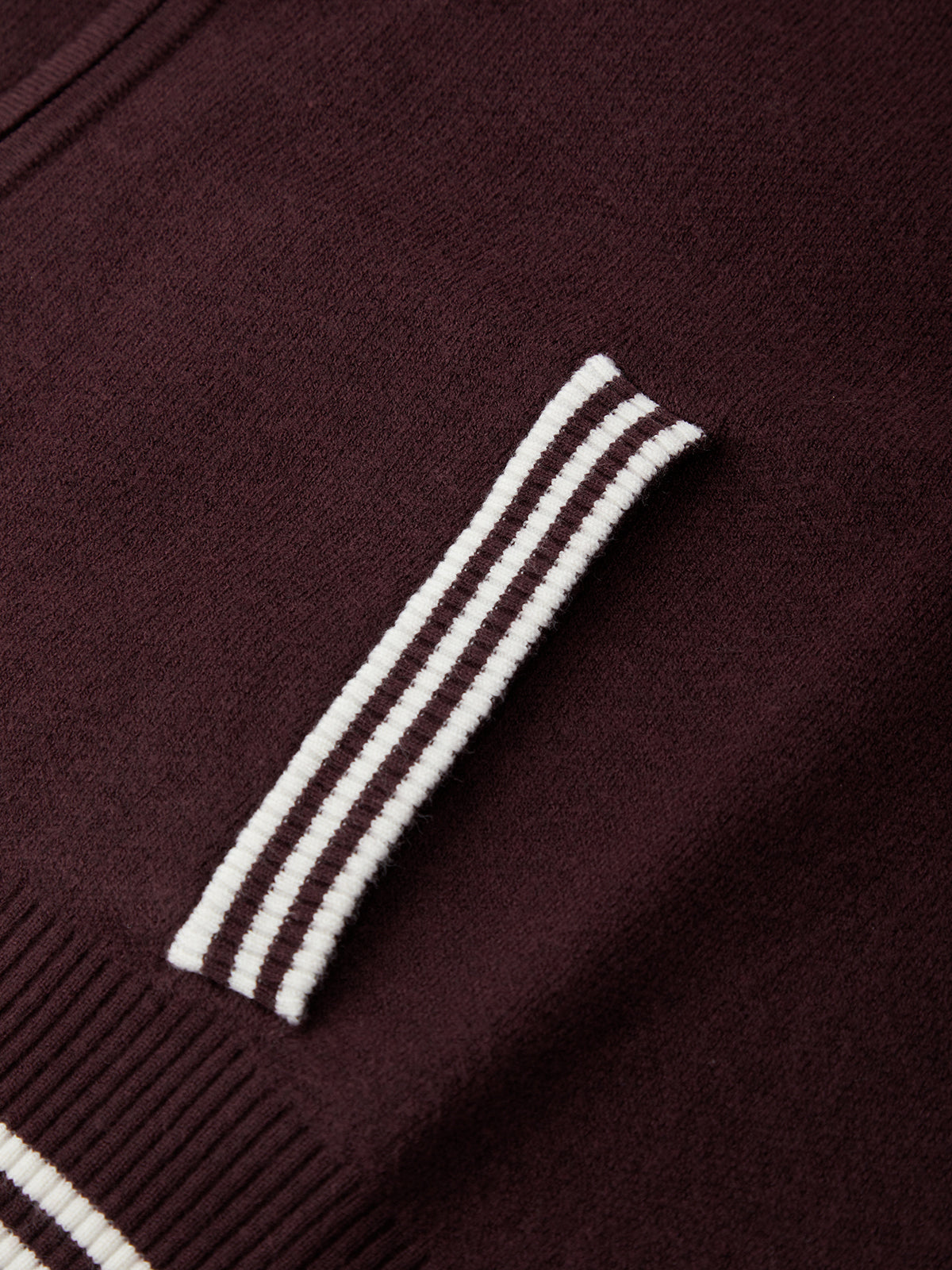 Close-up of a dark brown sweater with white stripes on the sleeve.