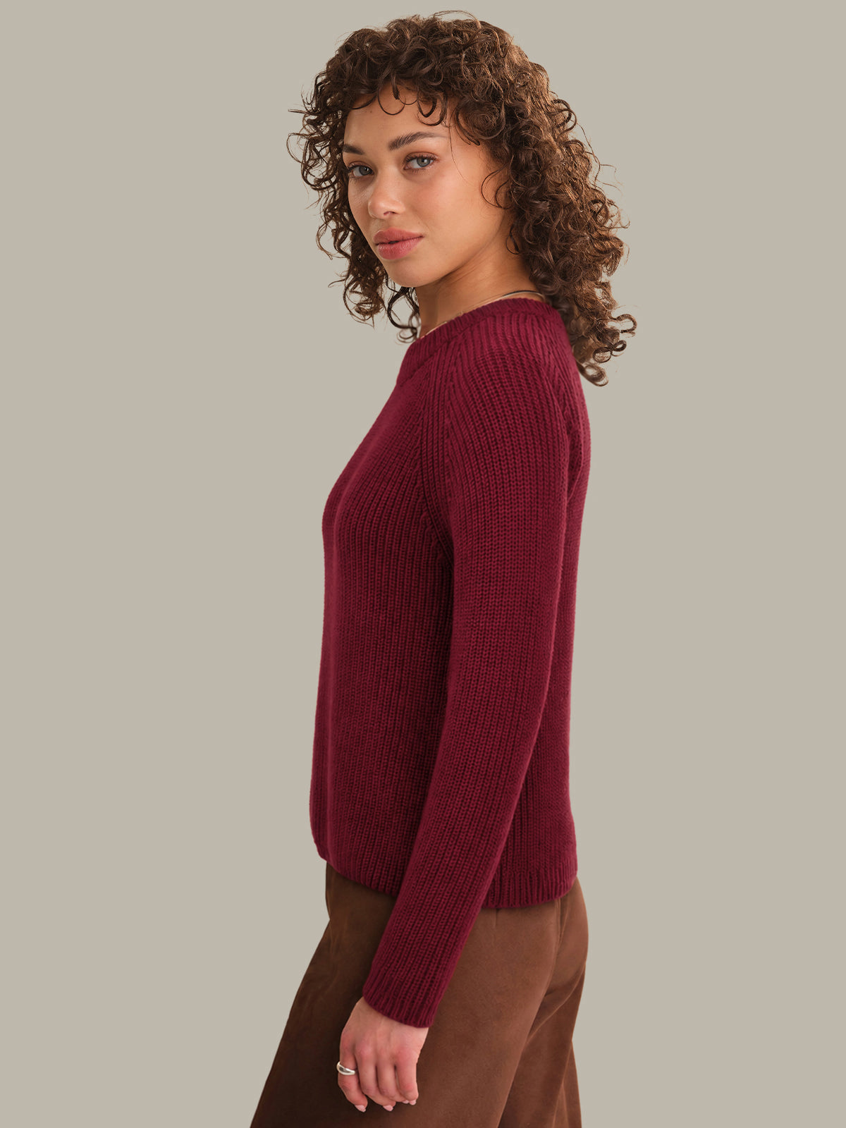Woman wearing a burgundy sweater against a plain background