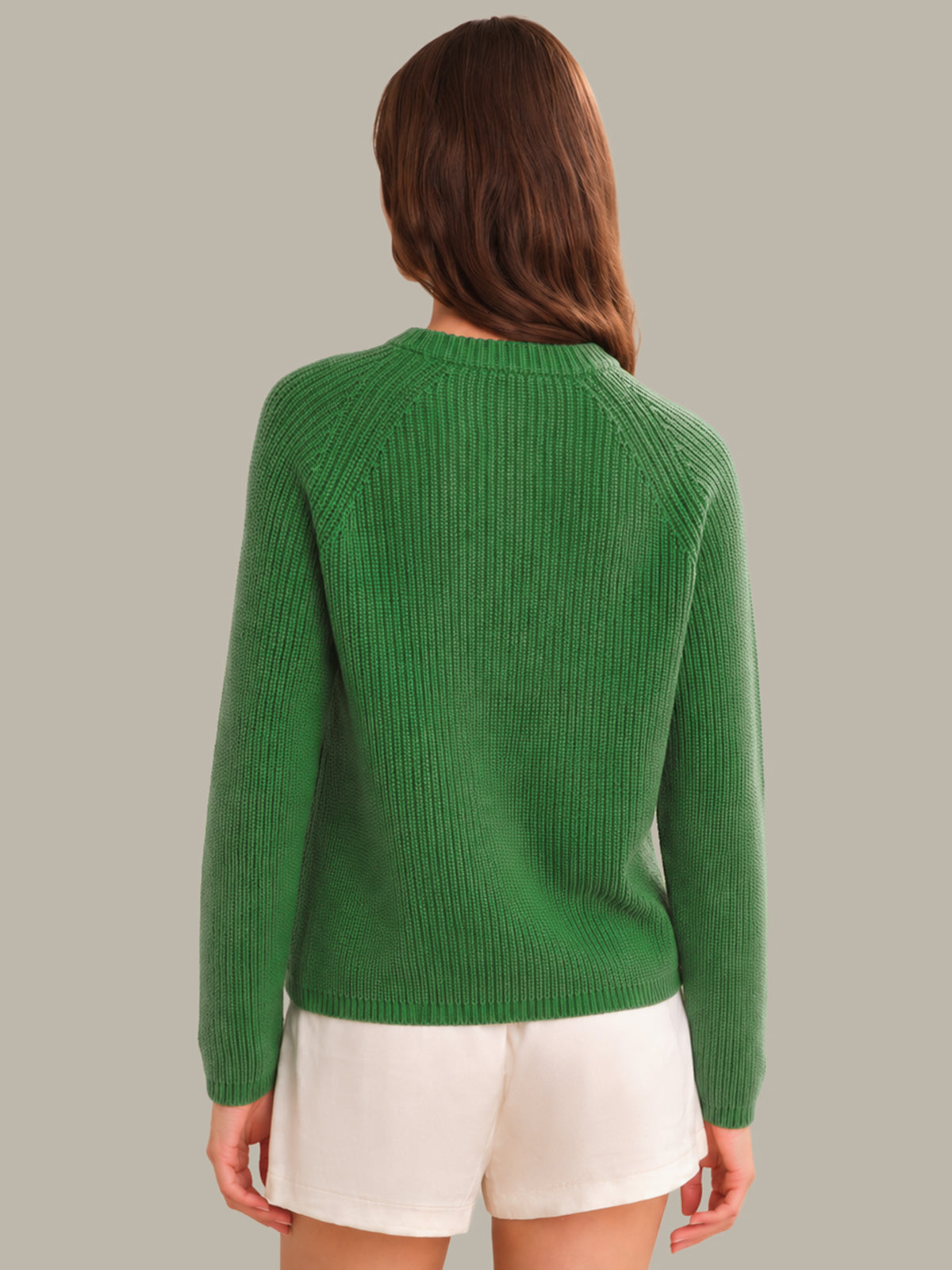 Person wearing a green sweater and white shorts on a plain background