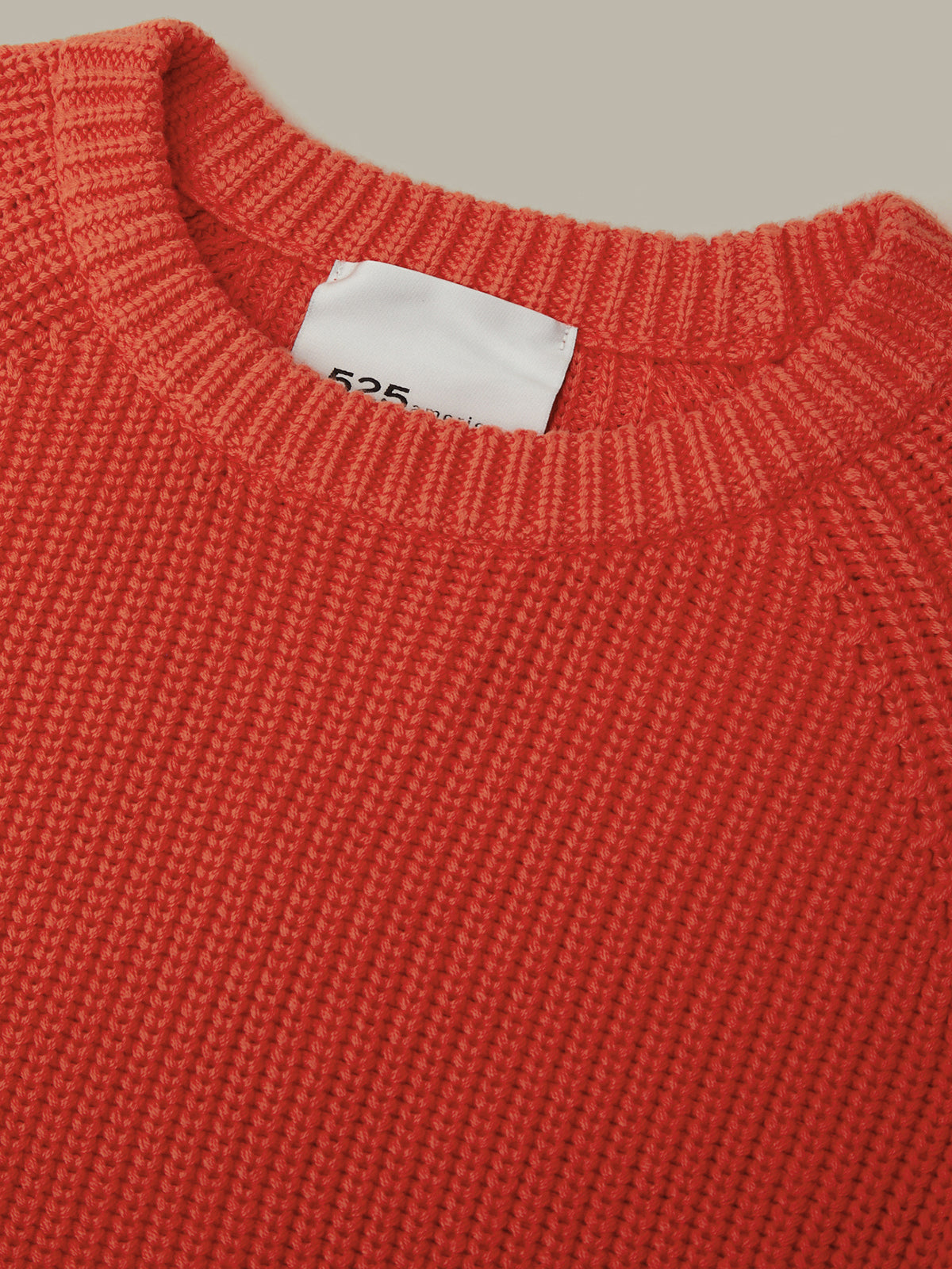 Close-up of a red sweater with a brand label on a beige background