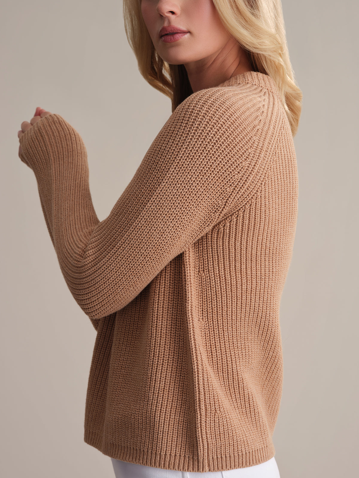 A blonde person is facing sideways against a light background in a camel-colored Jane crewneck shaker stitch cotton sweater, featuring ribbed sleeve and hem detailing.
