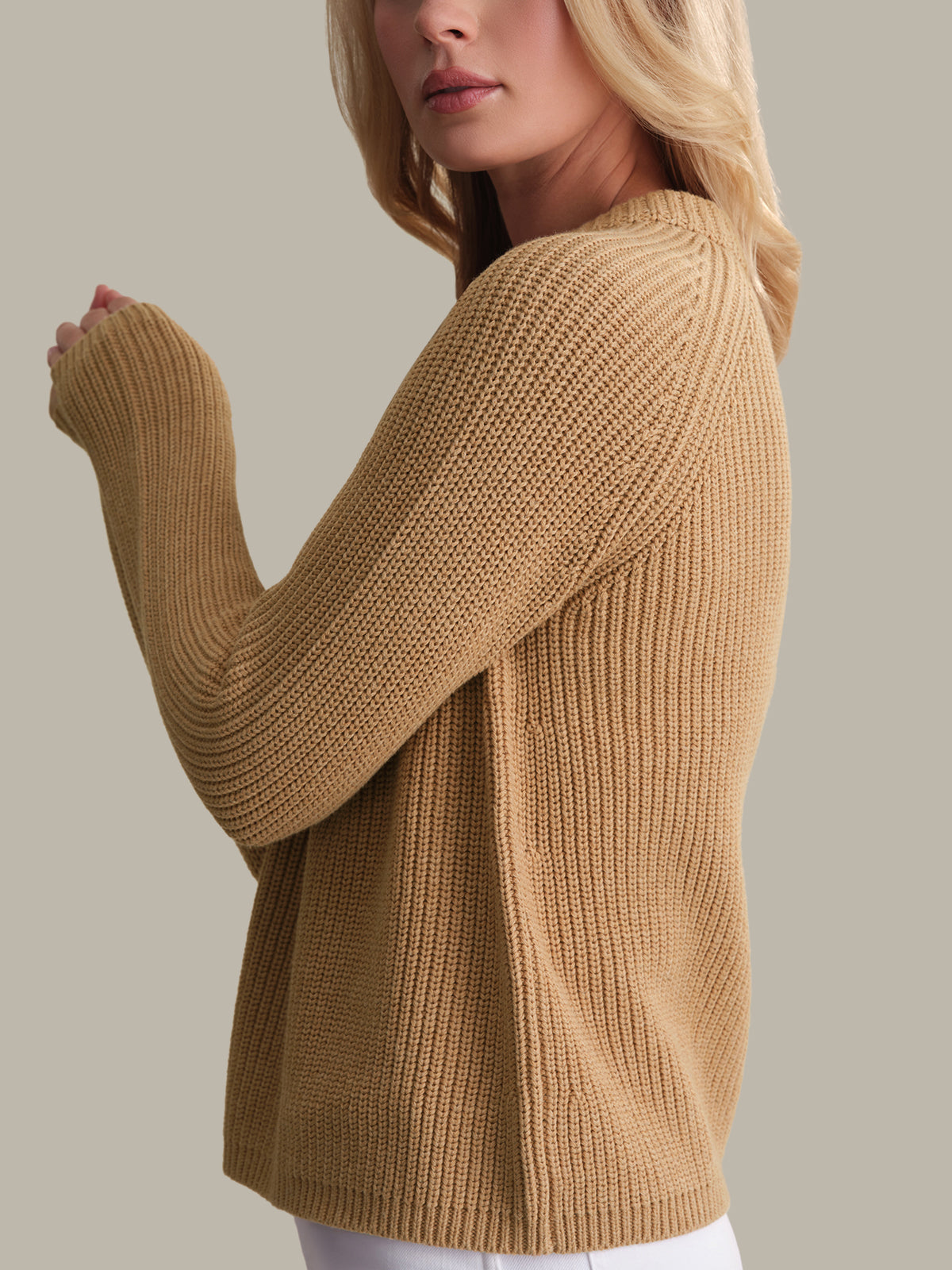 Woman wearing a beige sweater against a neutral background