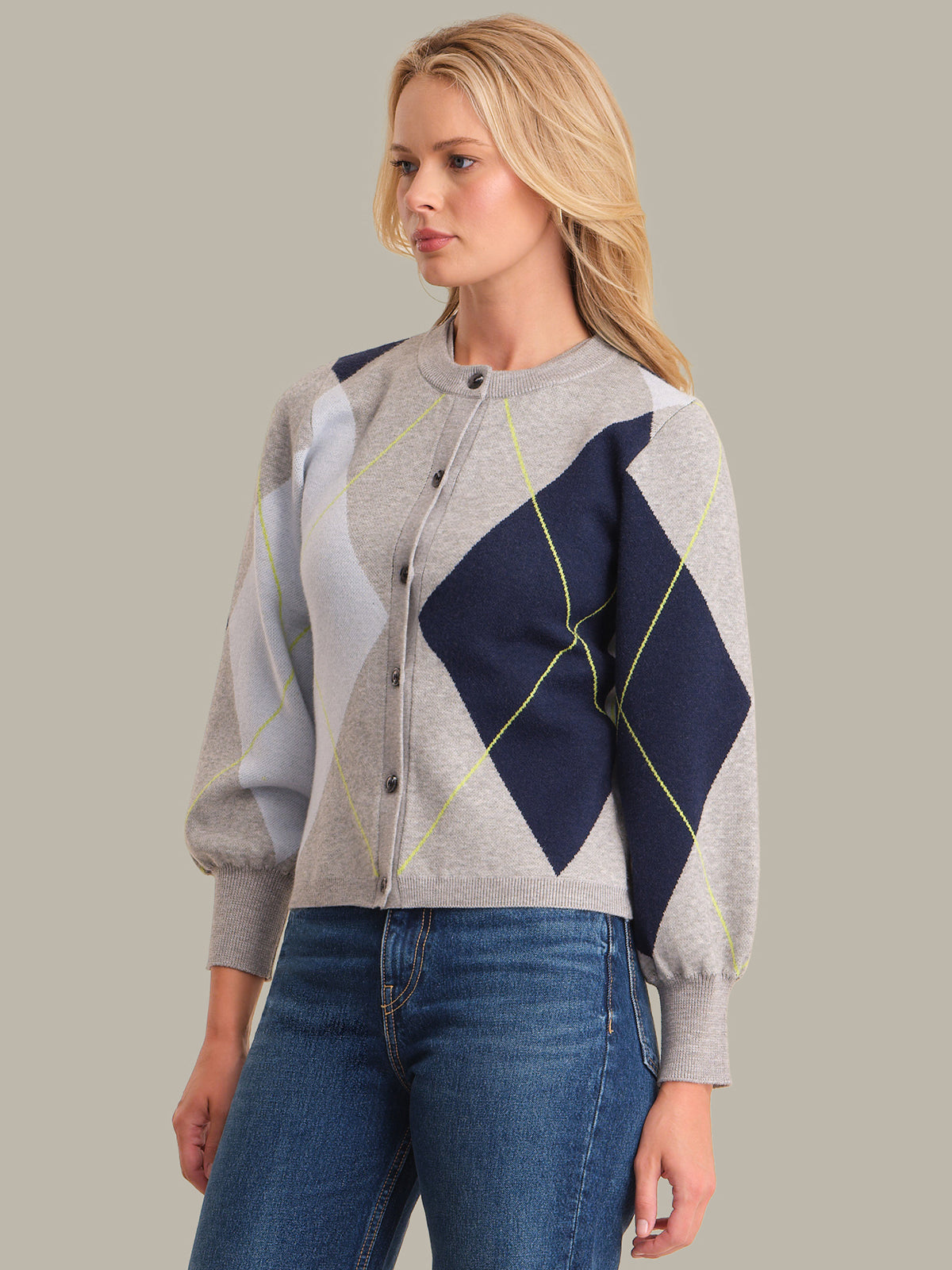 Woman wearing a patterned cardigan with a geometric design on a plain background