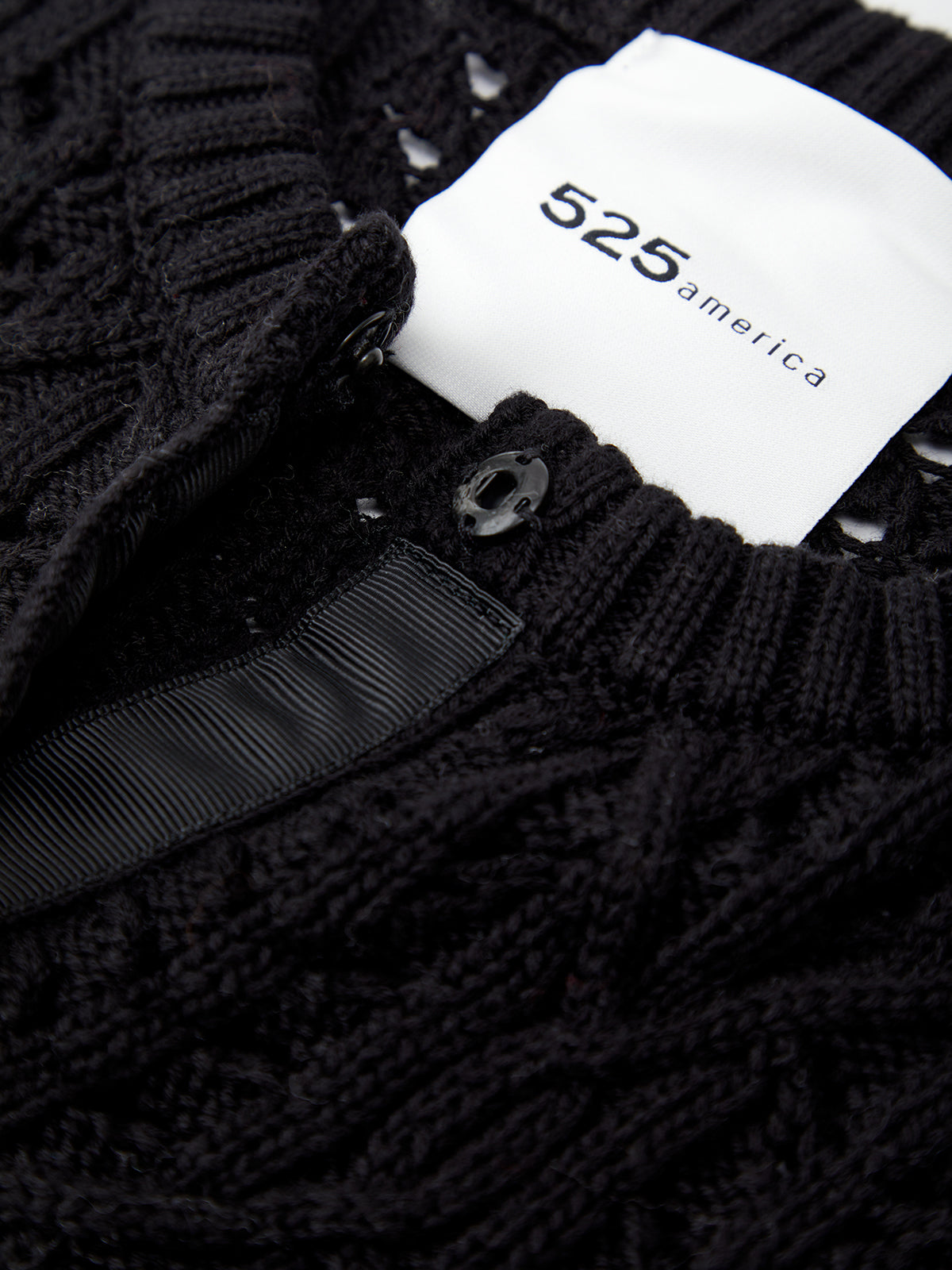 Close-up of a black textured garment with a white label displaying '525 America'.